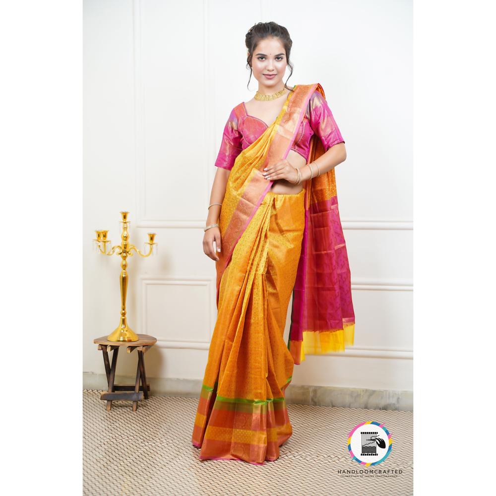 A woman stands elegantly in a yellow and red Banarasi tissue silk saree, showcasing the intricate print and soft drape of this luxurious garment.