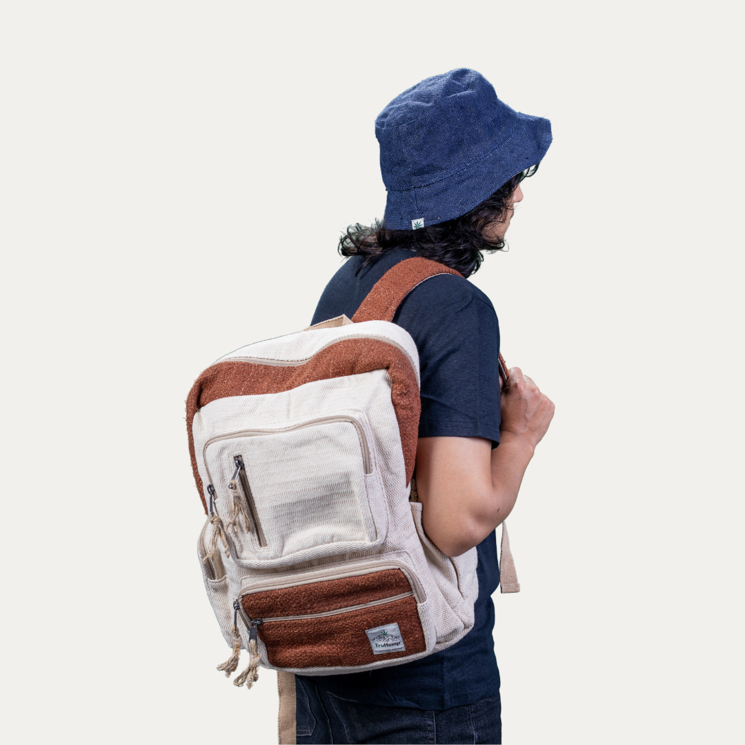 A man models a spacious, off-white handmade hemp backpack with multiple pockets and brown accents, perfect for eco-conscious individuals.