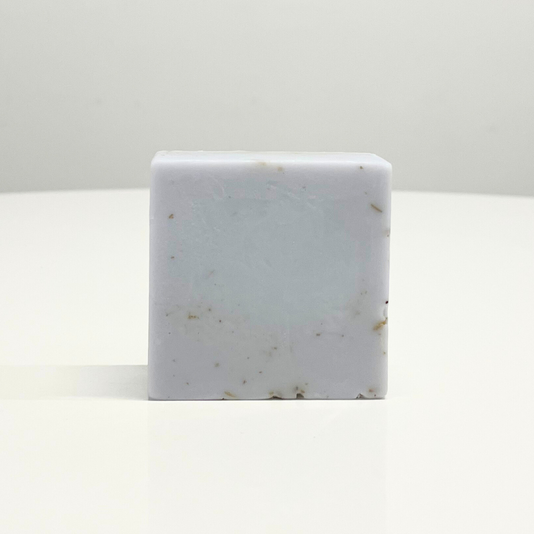 A single bar of handcrafted lavender soap. The soap is light purple with flecks of lavender throughout.