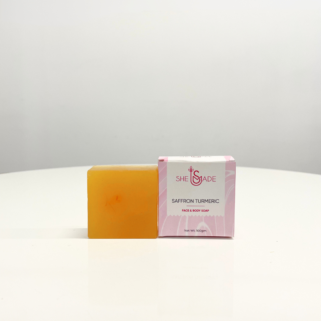 A single bar of handcrafted Saffron Turmeric soap sits beside its pink packaging, promising a luxurious and aromatic cleansing experience.