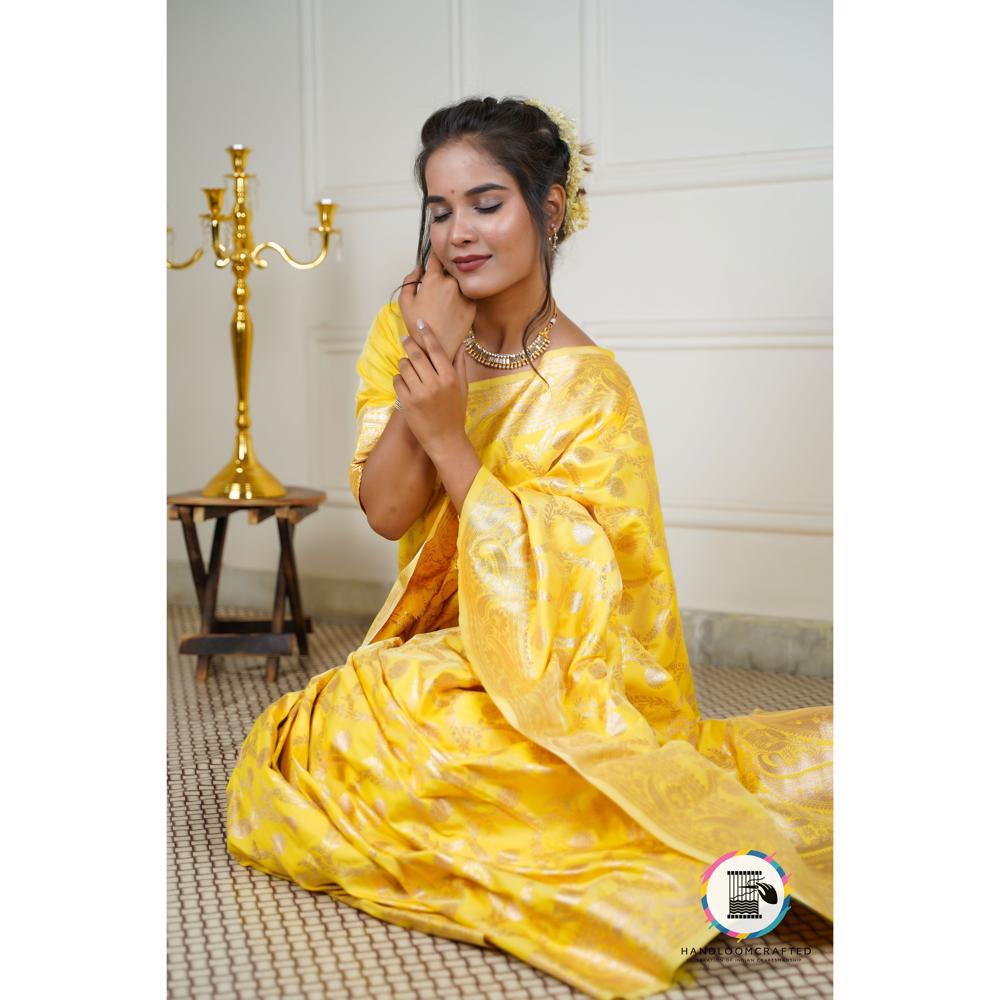 A woman draped in a vibrant Sunflower Yellow Banarasi Tissue Silk Saree with intricate gold patterns, showcasing its elegant drape and luxurious texture.