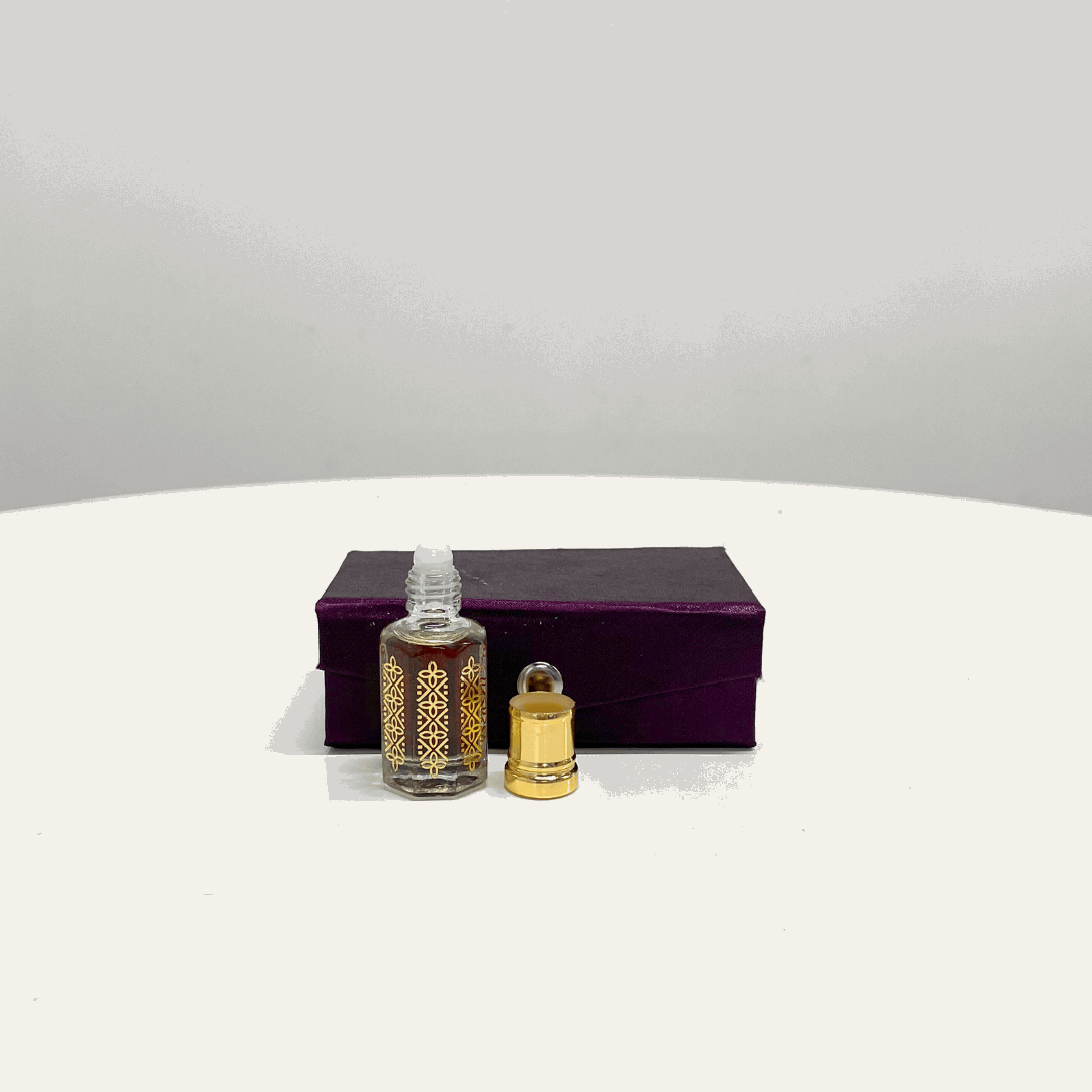 A small, ornate bottle of Blue Lotus Attar Unisex perfume, with its gold cap open beside it, displayed on a purple presentation box.