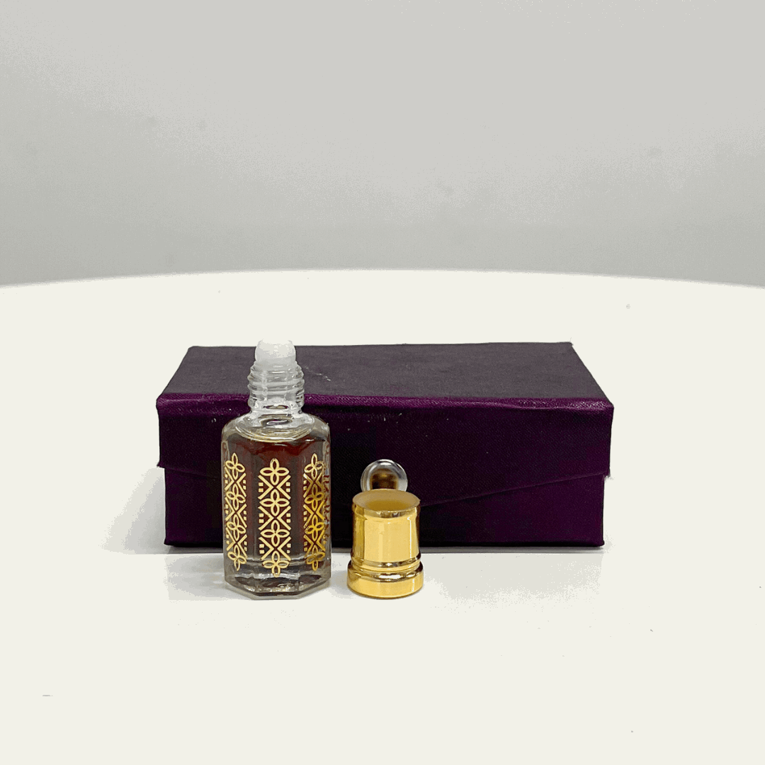 A bottle of Black Oud Attar unisex fragrance with its gold cap off, presented in a luxurious purple box.