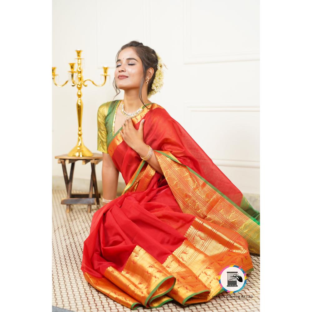 A woman gracefully drapes a "Green Red Printed Plain Soft Banarasi Tissue Silk Saree," its vibrant red fabric and intricate gold and green border catching the light.