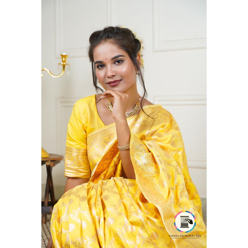 A woman wearing a vibrant sunflower yellow Banarasi saree made from luxurious tissue silk, showcasing intricate woven patterns.