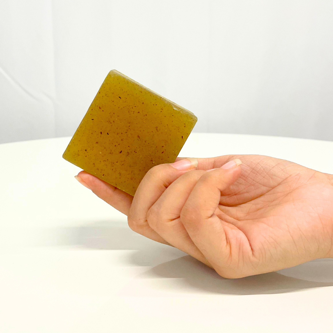 Hand holding a square bar of handcrafted aloe vera & neem soap.