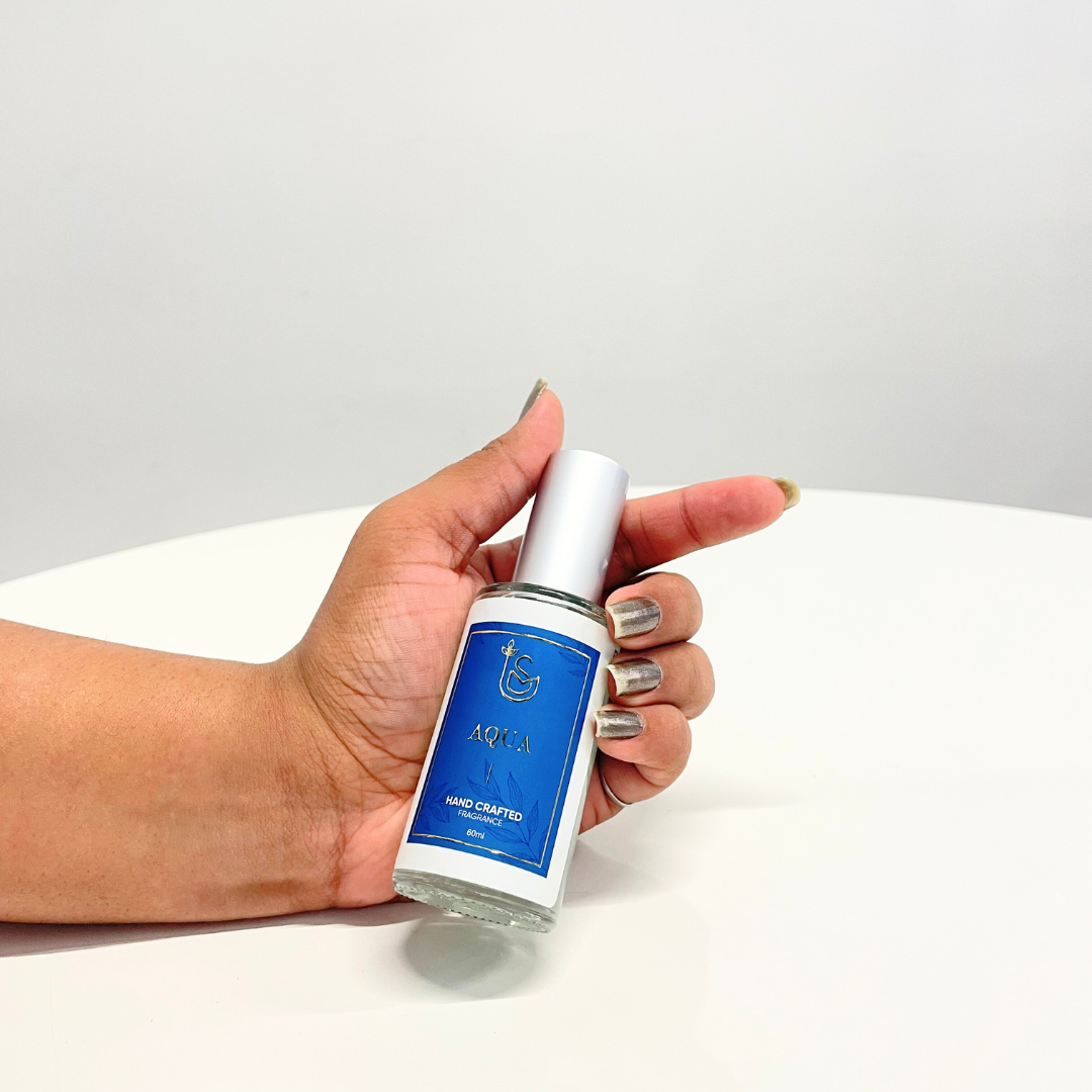 A hand holds a bottle of "The Aquanautical Perfume" against a white background, showcasing the unisex fragrance.