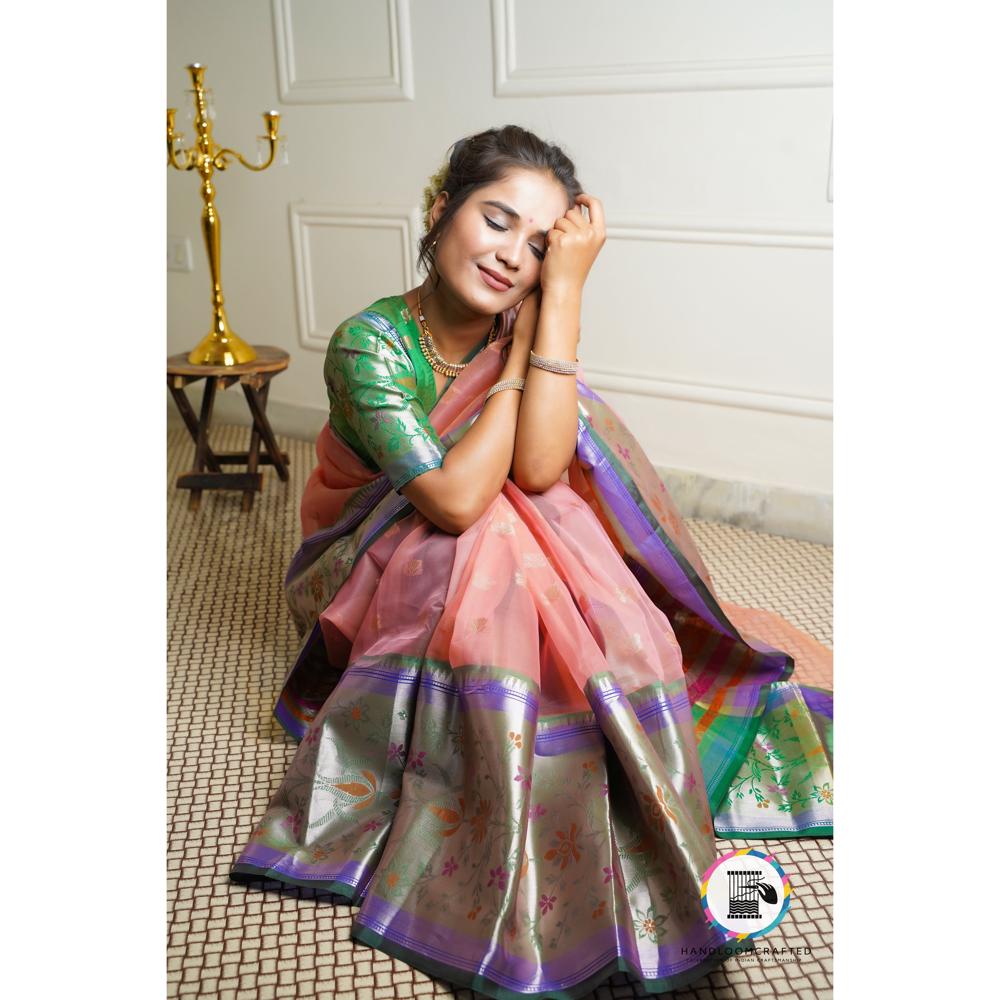 A woman gracefully drapes a Green Peach Printed Soft Banarasi Tissue Silk Saree, showcasing its intricate floral patterns and vibrant colors.