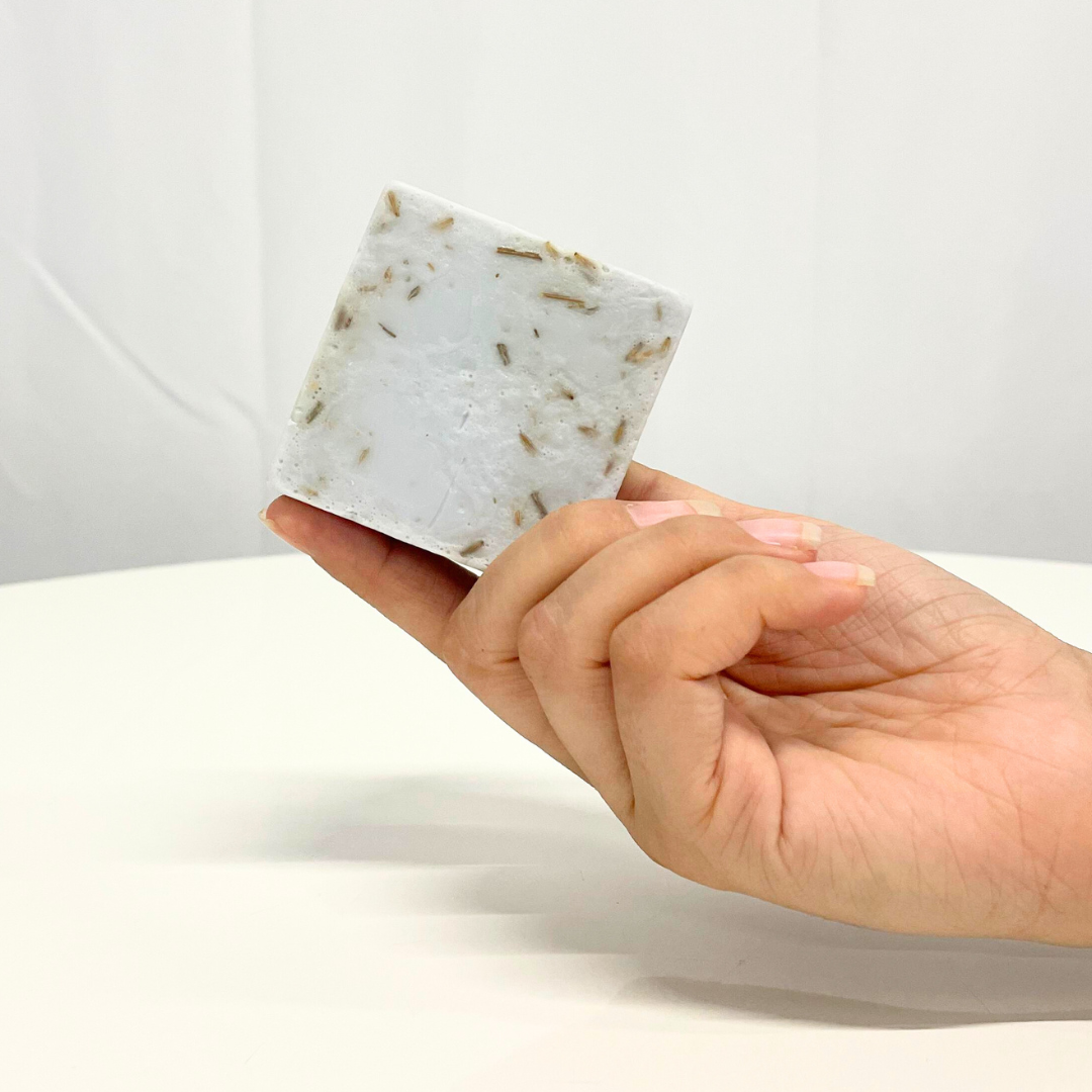 Handcrafted lavender soap bar held in a hand. This natural soap is perfect for healing body acne and all skin types.