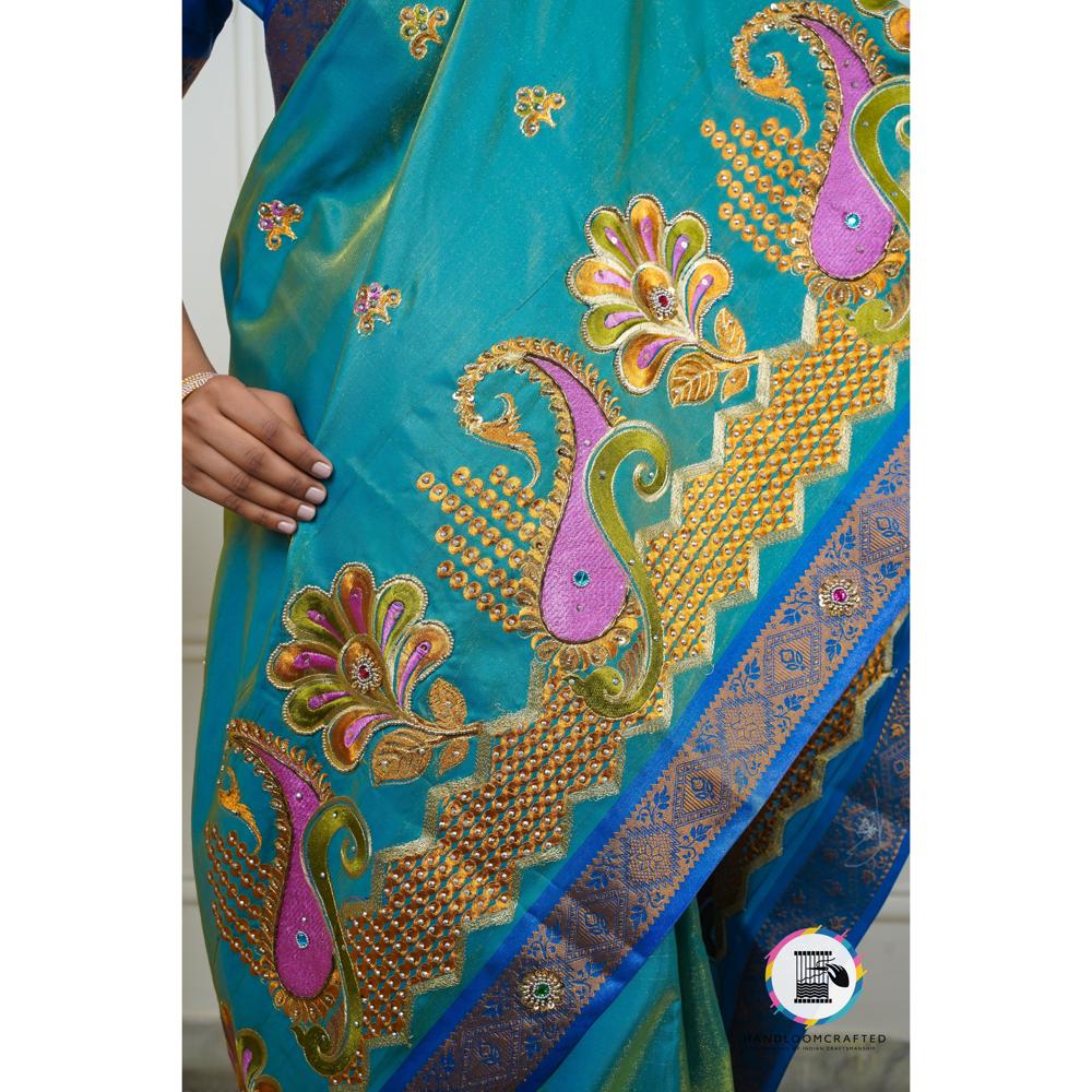 Peacock blue Banarasi tissue silk saree with intricate paisley and floral embroidery embellished with gold and colorful beads.