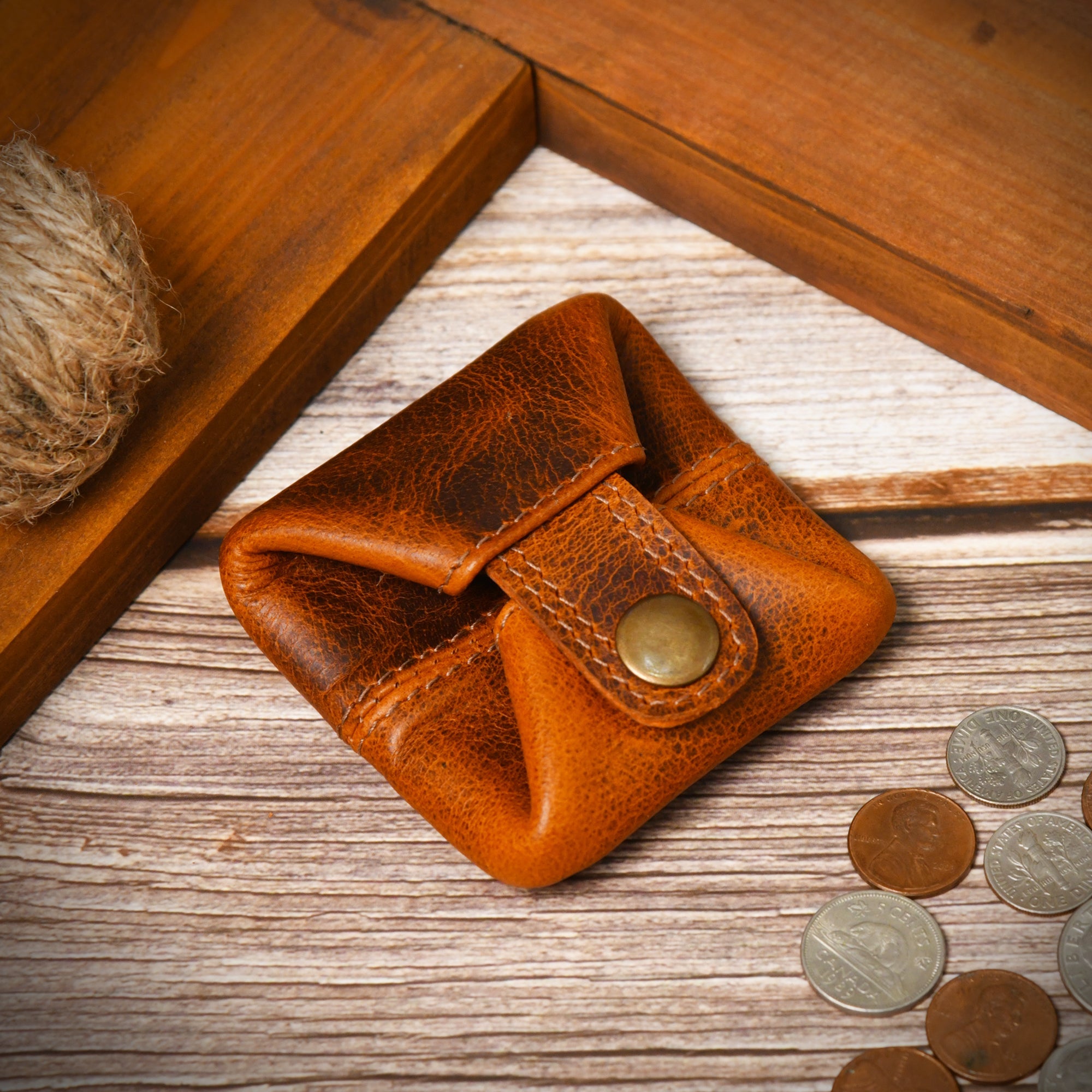 Slim, cinnamon brown leather coin purse with a snap closure, shown with a few coins to demonstrate size.