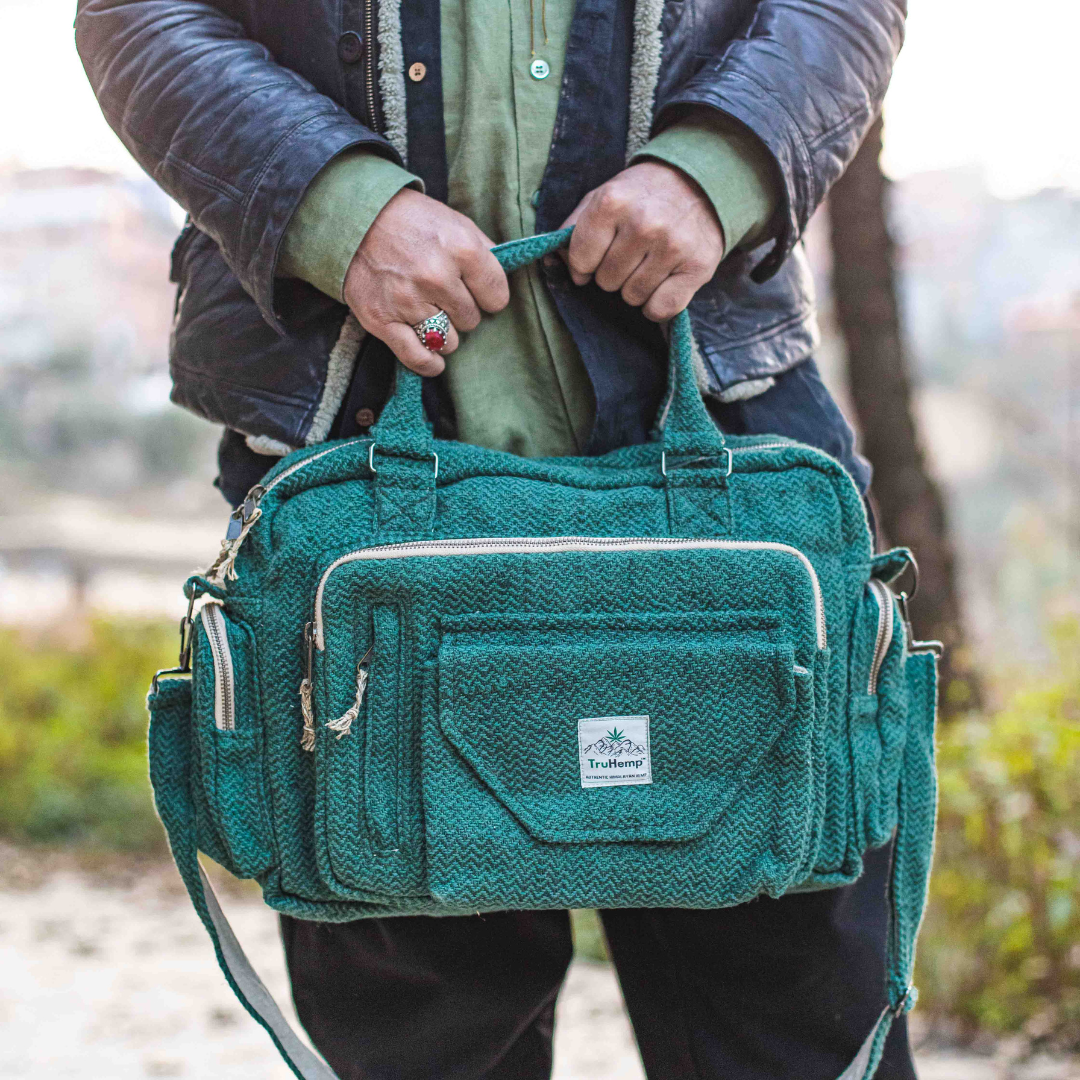 Stylish green Himalayan Hemp Laptop Side Bag with multiple pockets and an adjustable strap, held by a person.