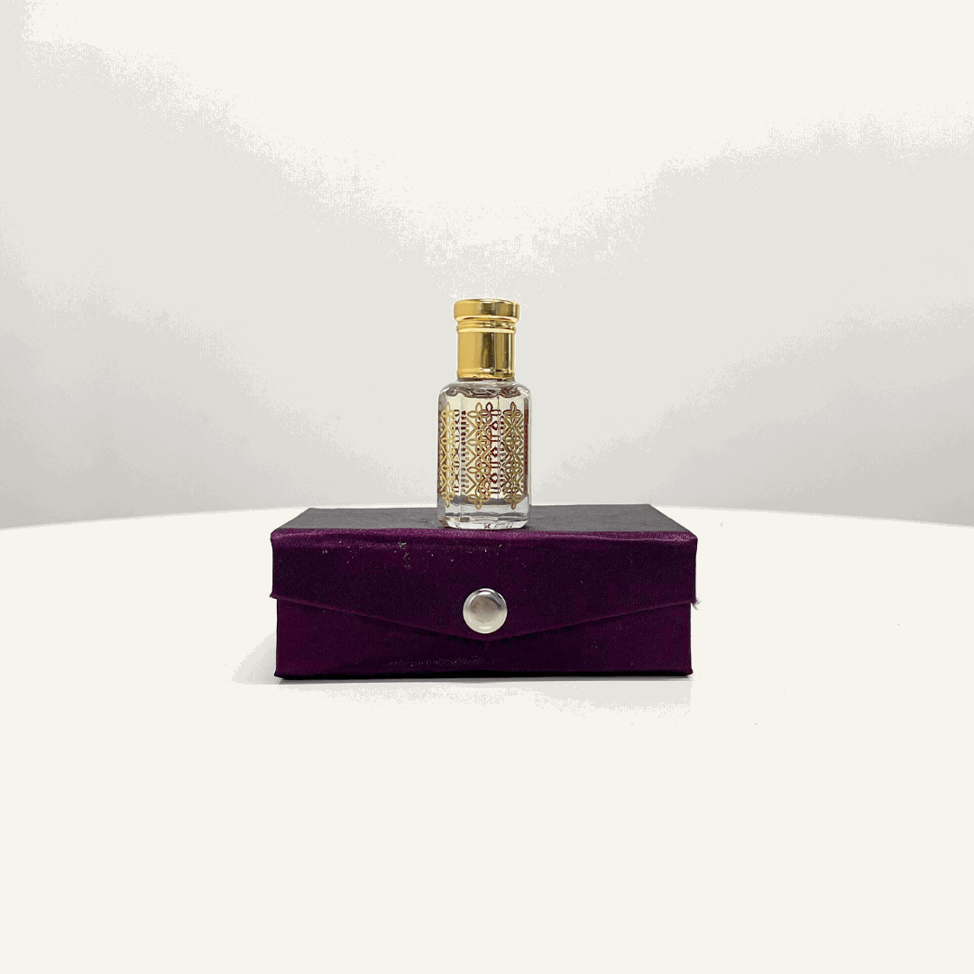 A bottle of Arabic Oud Attar Unisex perfume, with an ornate gold and red design, displayed on a purple presentation box.