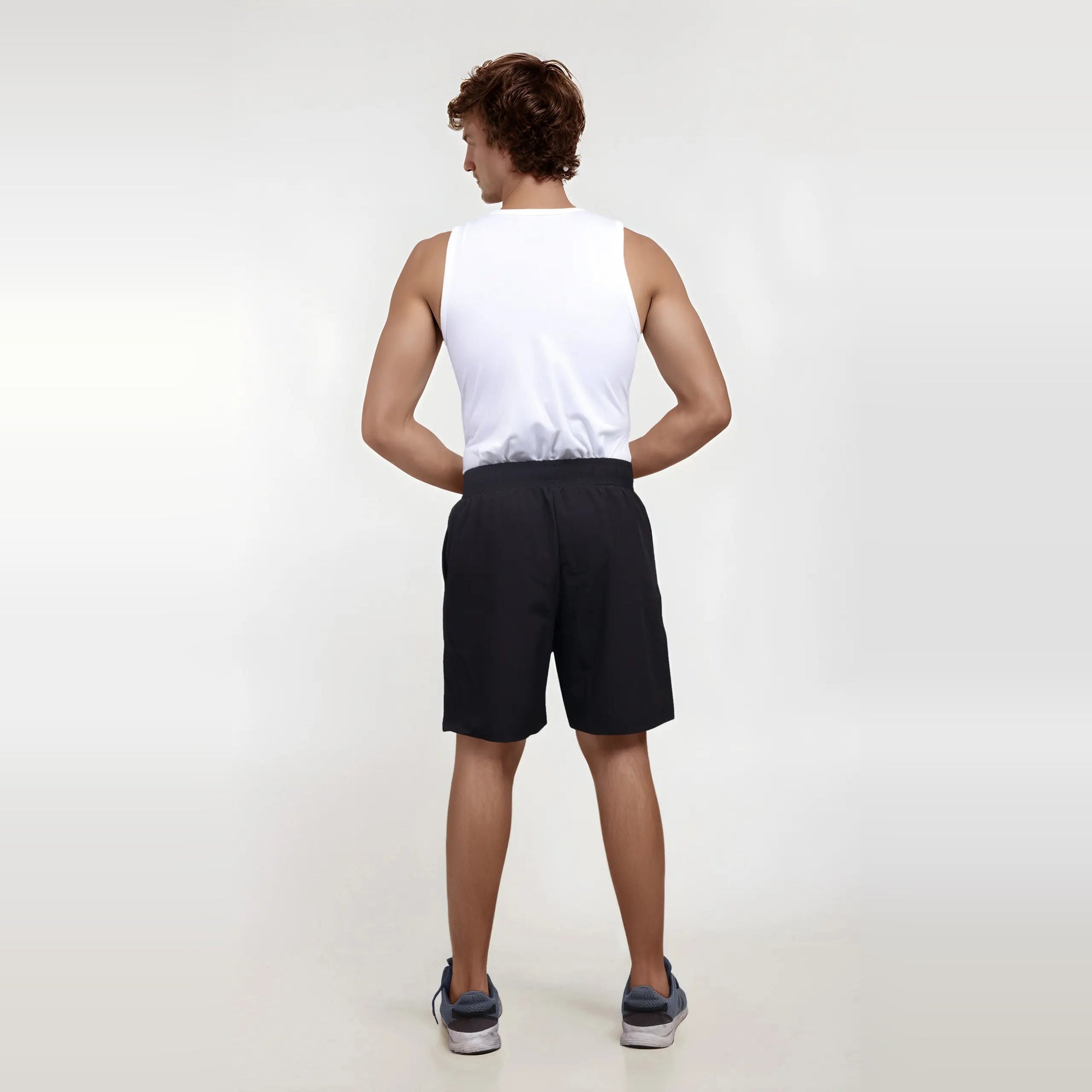 Man wearing wrinkle-free, dry-fit black shorts from the back, perfect for sports and the gym.