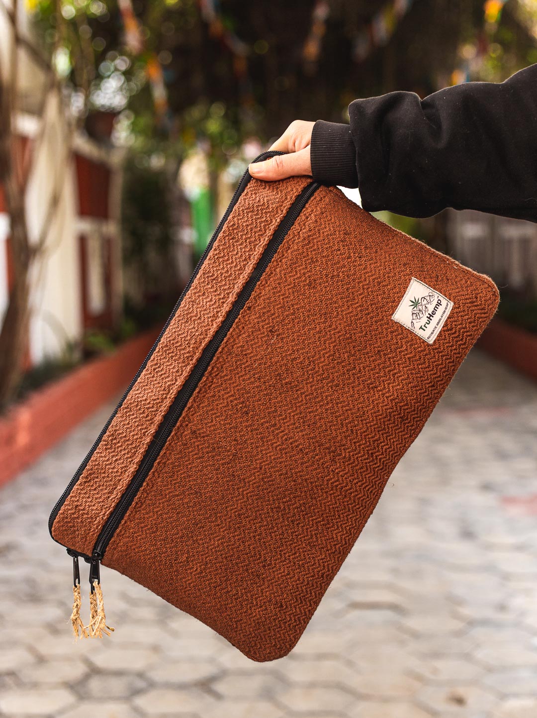 Hand holding a rustic brown Himalayan Natural Hemp Laptop Sleeve, showcasing its eco-friendly and durable design.