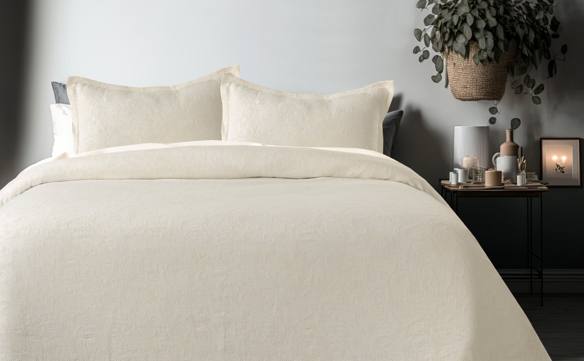 Milky white waffle-textured cotton bedspread with subtle gardenia pattern, shown on a bed with two matching pillow shams.