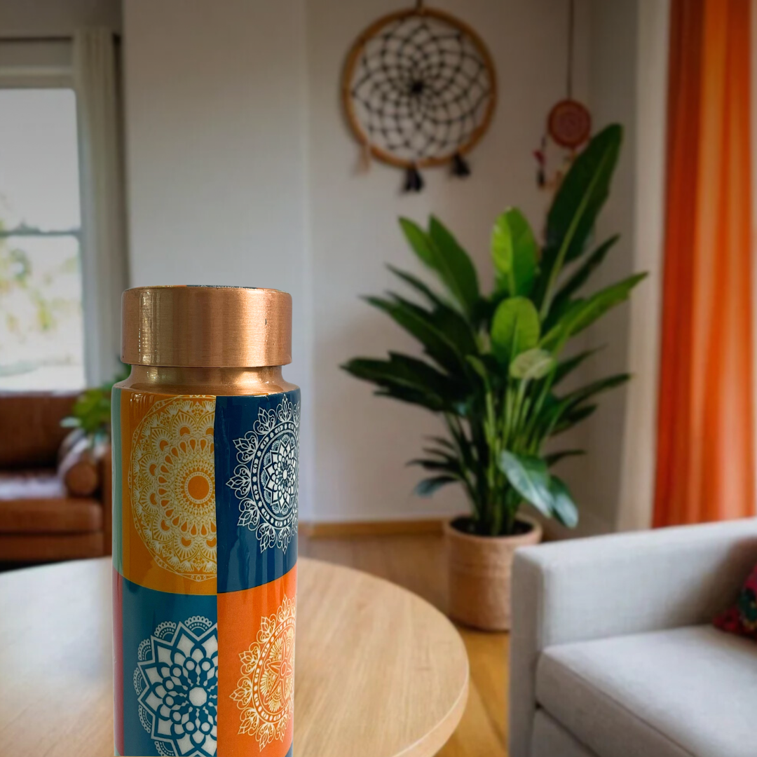 Multicolor copper water bottle with a bohemian mandala pattern, shown in a home living room setting.