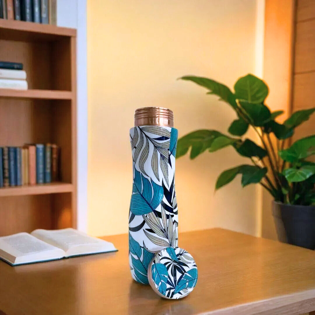 Stylish leaf-print, 1-liter pure copper water bottle with open lid on table. Leakproof and durable, this authentic copper bottle offers antibacterial benefits.