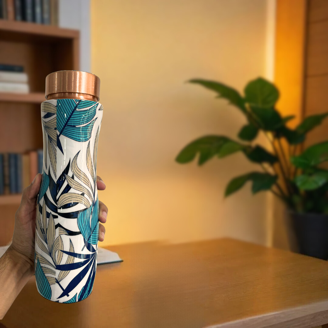 Hand holding a 1 liter copper water bottle with a leaf print. The bottle has a copper lid and is leakproof.