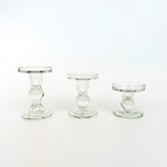 Three clear glass candle holders in small, medium, and large sizes. These elegant Paradise candle holders feature a classic pedestal design.