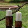 Set of 3 unscented white pillar candles in varying sizes, nestled in rustic brown wooden holders.