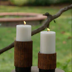 Set of 3 unscented white pillar candles in varying sizes, nestled in rustic brown wooden holders.