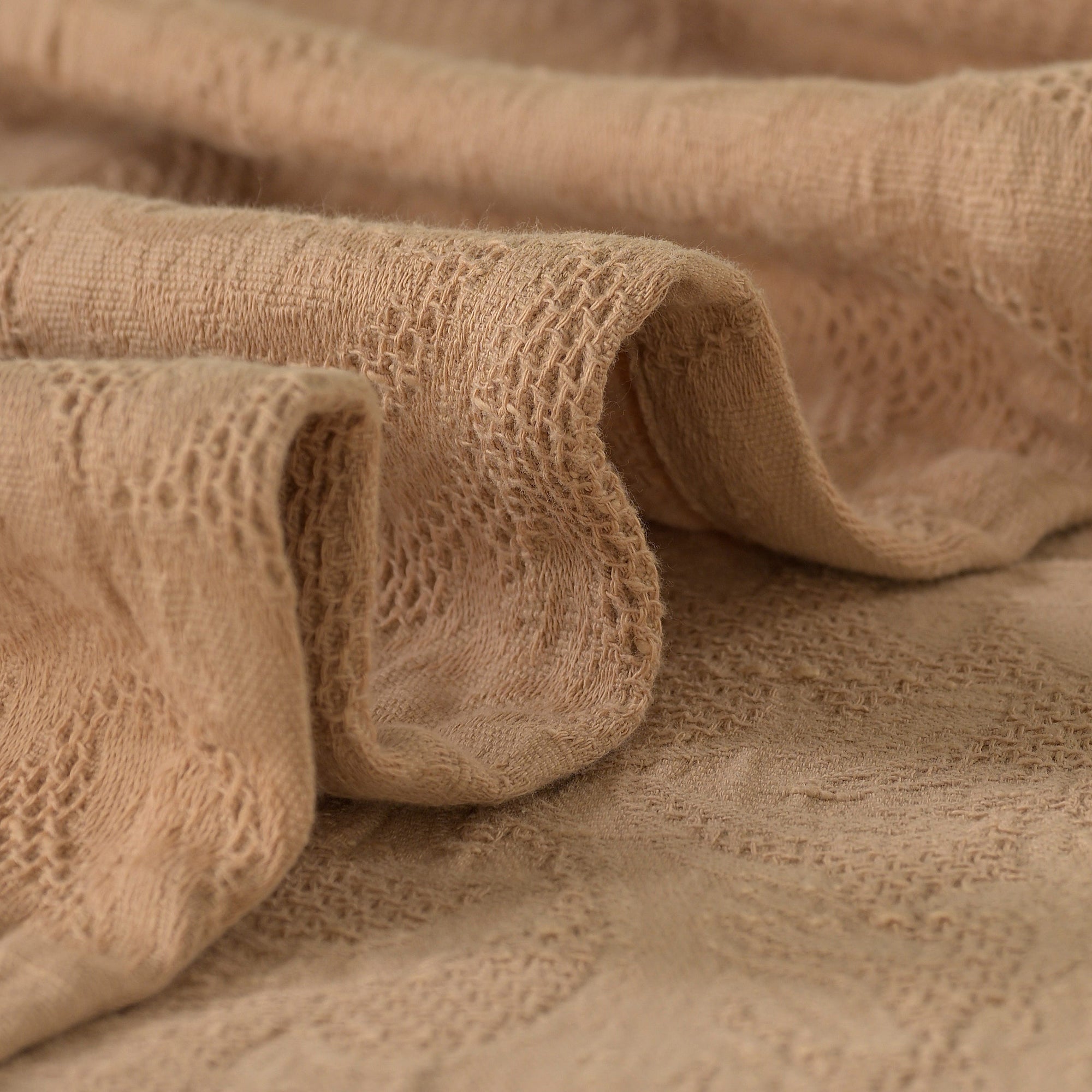 Close-up of the soft, textured weave of a tanned pink Gardenia waffle cotton bed sheet.