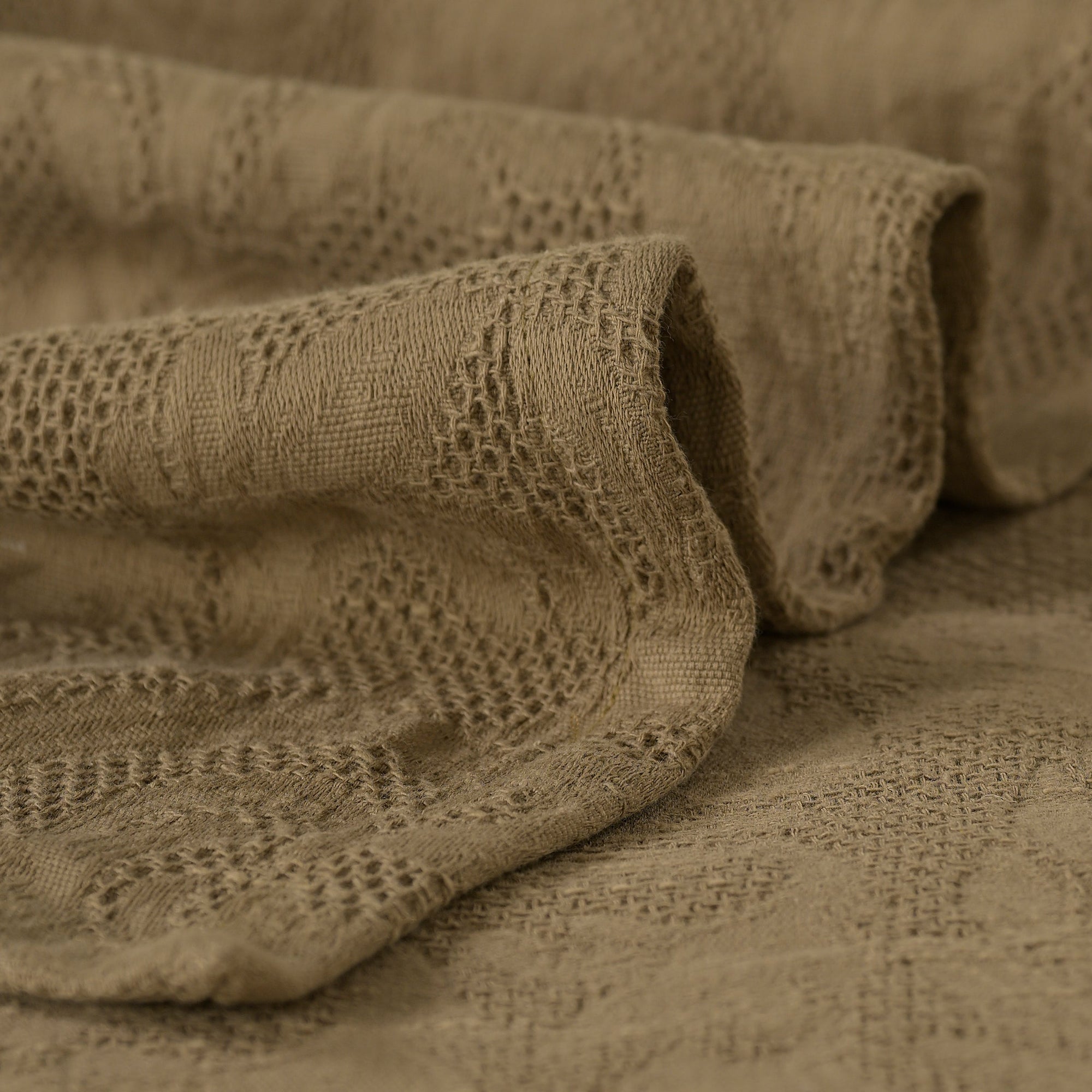 Close-up of sage green waffle weave on a Gardenia cotton bed sheet, known for its ultra-soft feel.