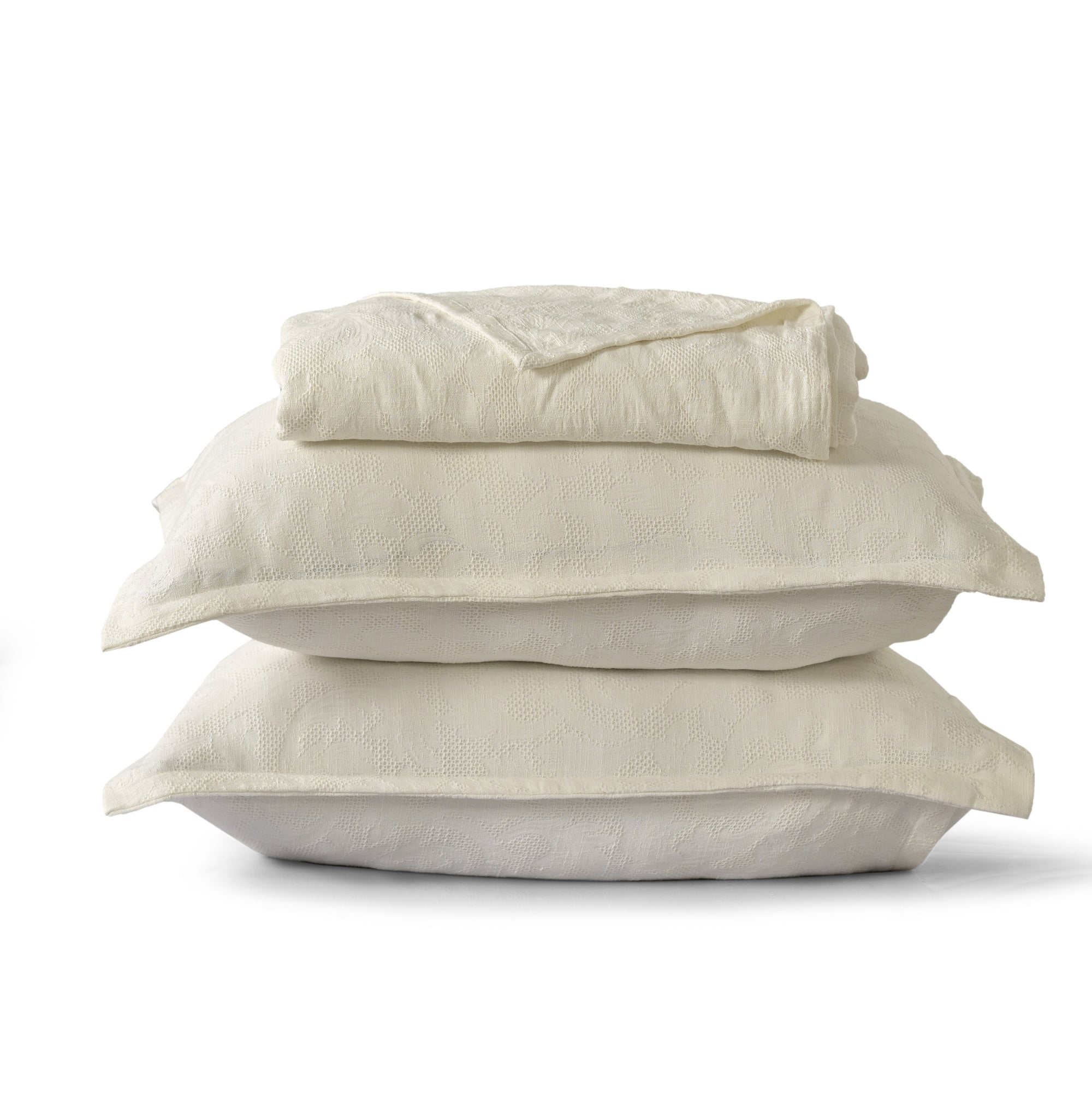 Milky white waffle-textured cotton bedspread and two matching pillow shams neatly stacked against a white background.