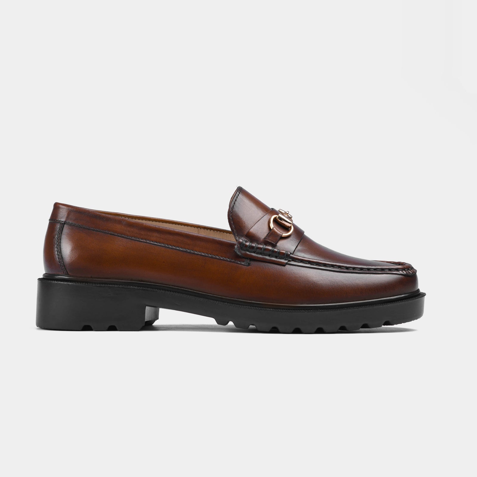 Pair of brown leather loafers with a gold buckle detail, featuring Solesculpt Lite technology for comfort.