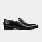 A pair of Arin Black Leather Loafers with a silver metal accent on the vamp, shown from the side.