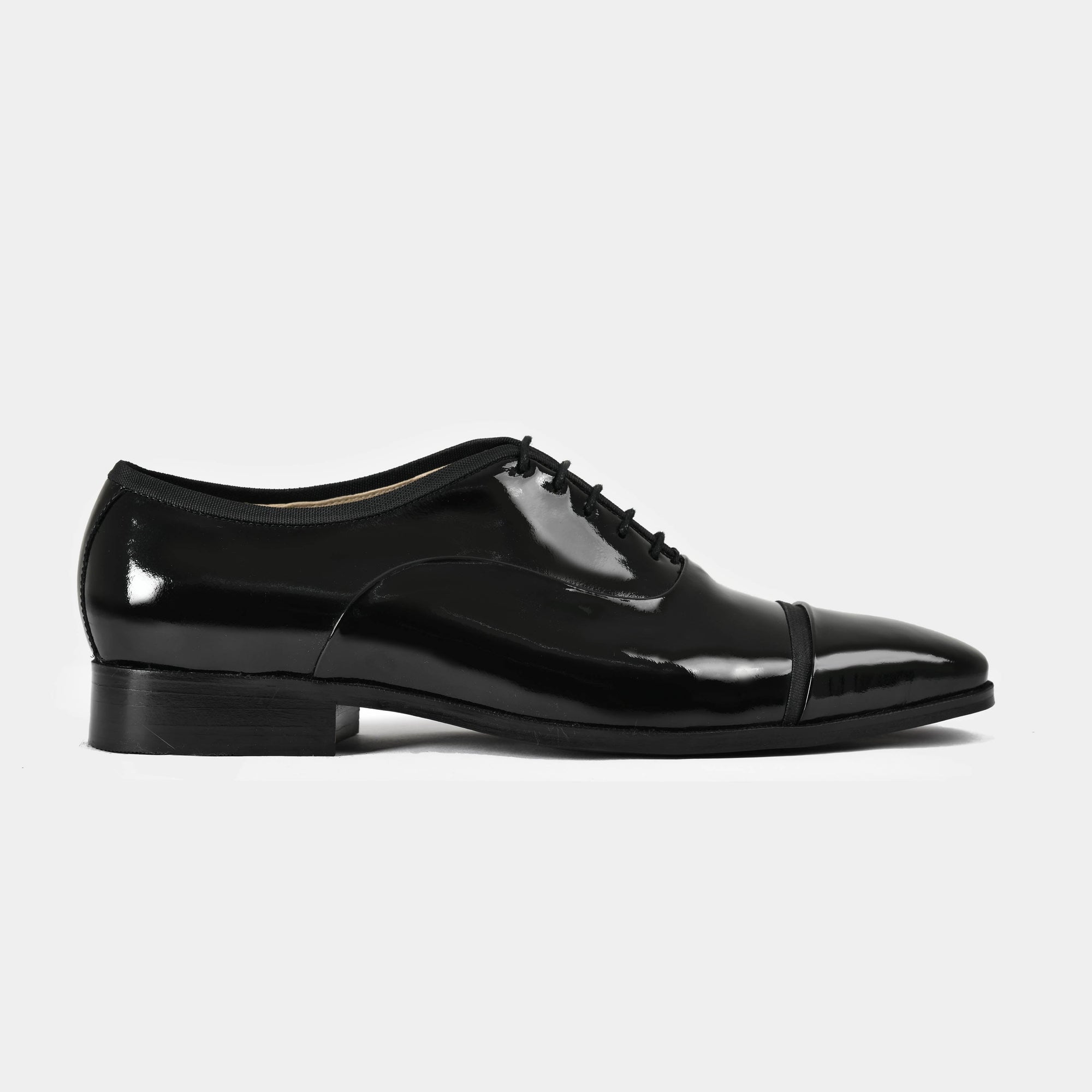 A side view of black Lsandro Patent Leather Laceups with a cap toe design.