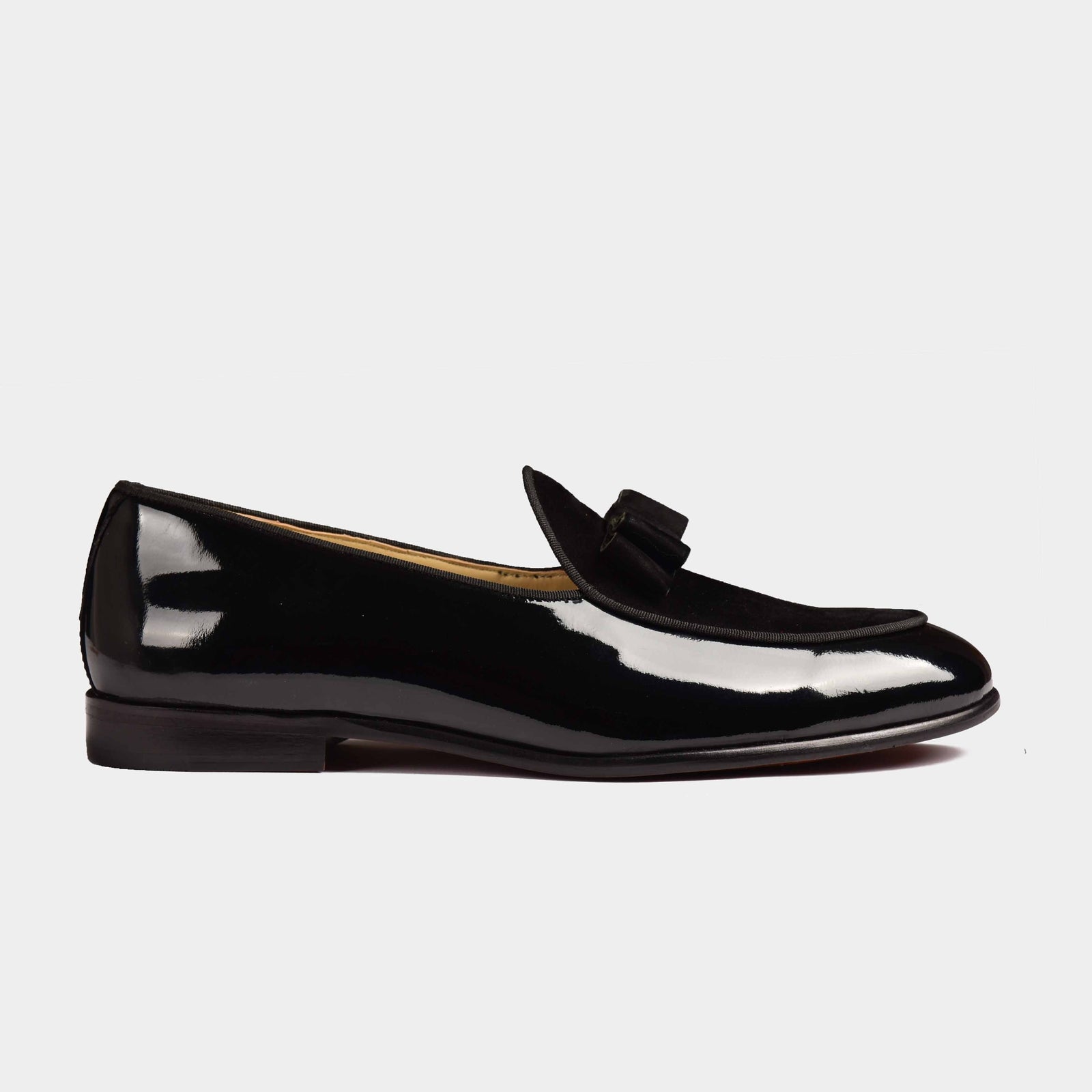 A pair of men's Arno loafers in shiny black patent calf leather. The loafers feature a sleek silhouette with a subtle bow-tie detail on the vamp.