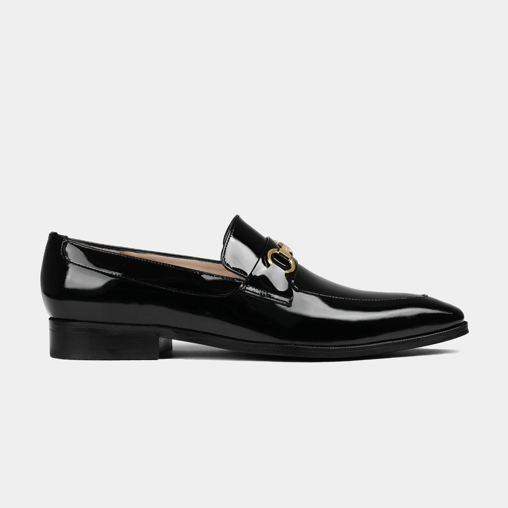 Pair of black Santos Patent Leather Loafers with gold buckle detail, shown from the side.