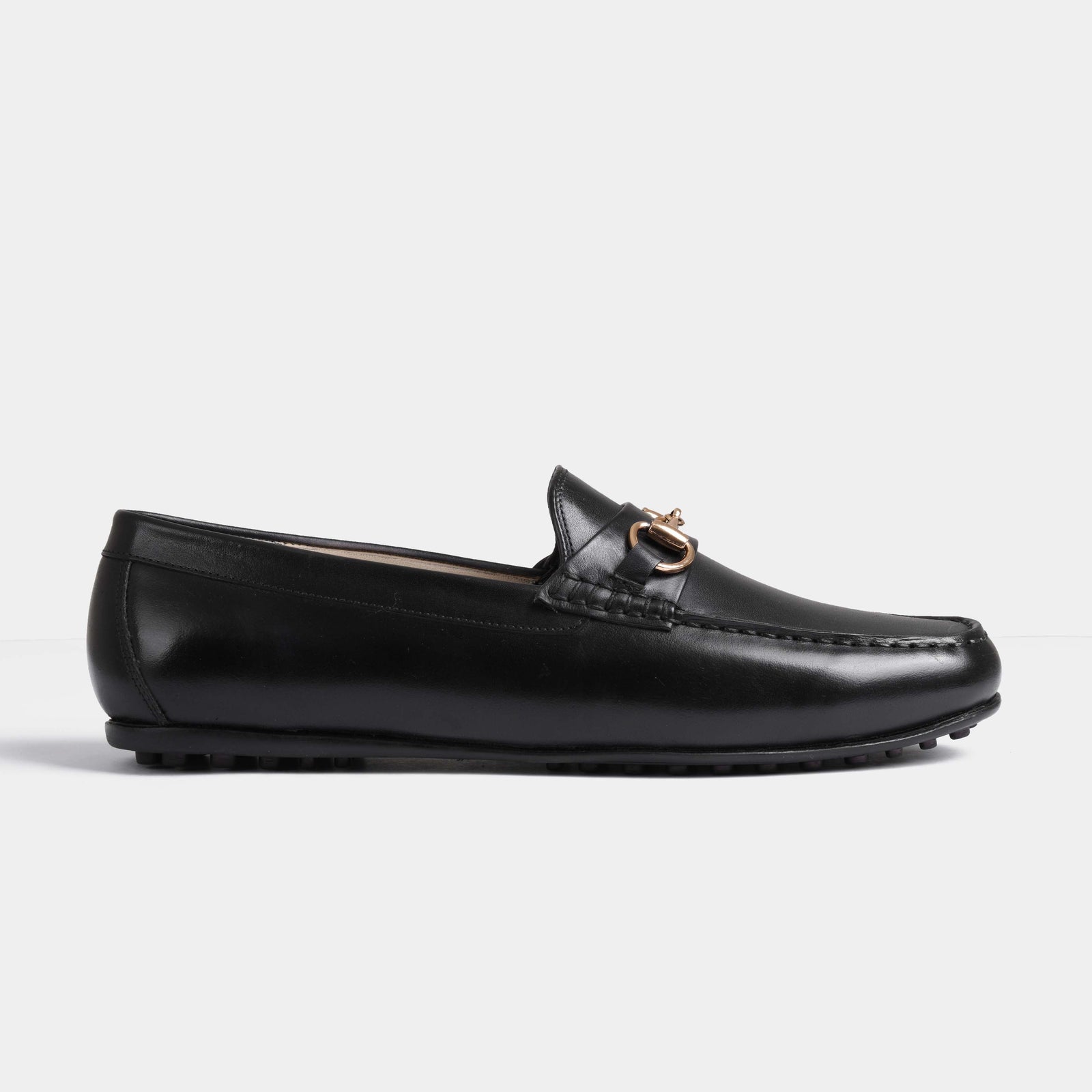 A side view of the Marco Black Leather Driving Loafers showcasing the sleek black leather and gold metal buckle detail.