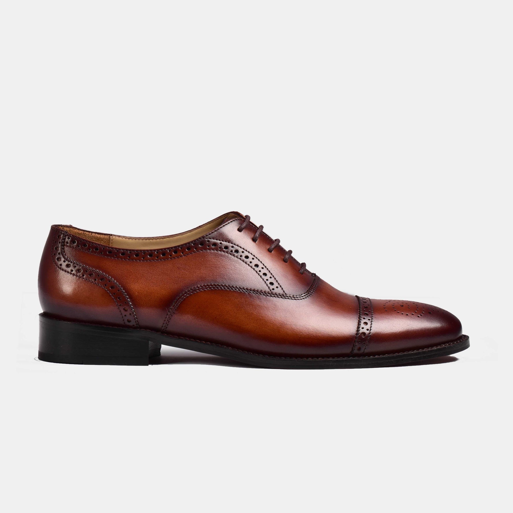 Side view of a brown leather Steven Brogue Cap Toe Lace Up shoe with decorative embellishments.