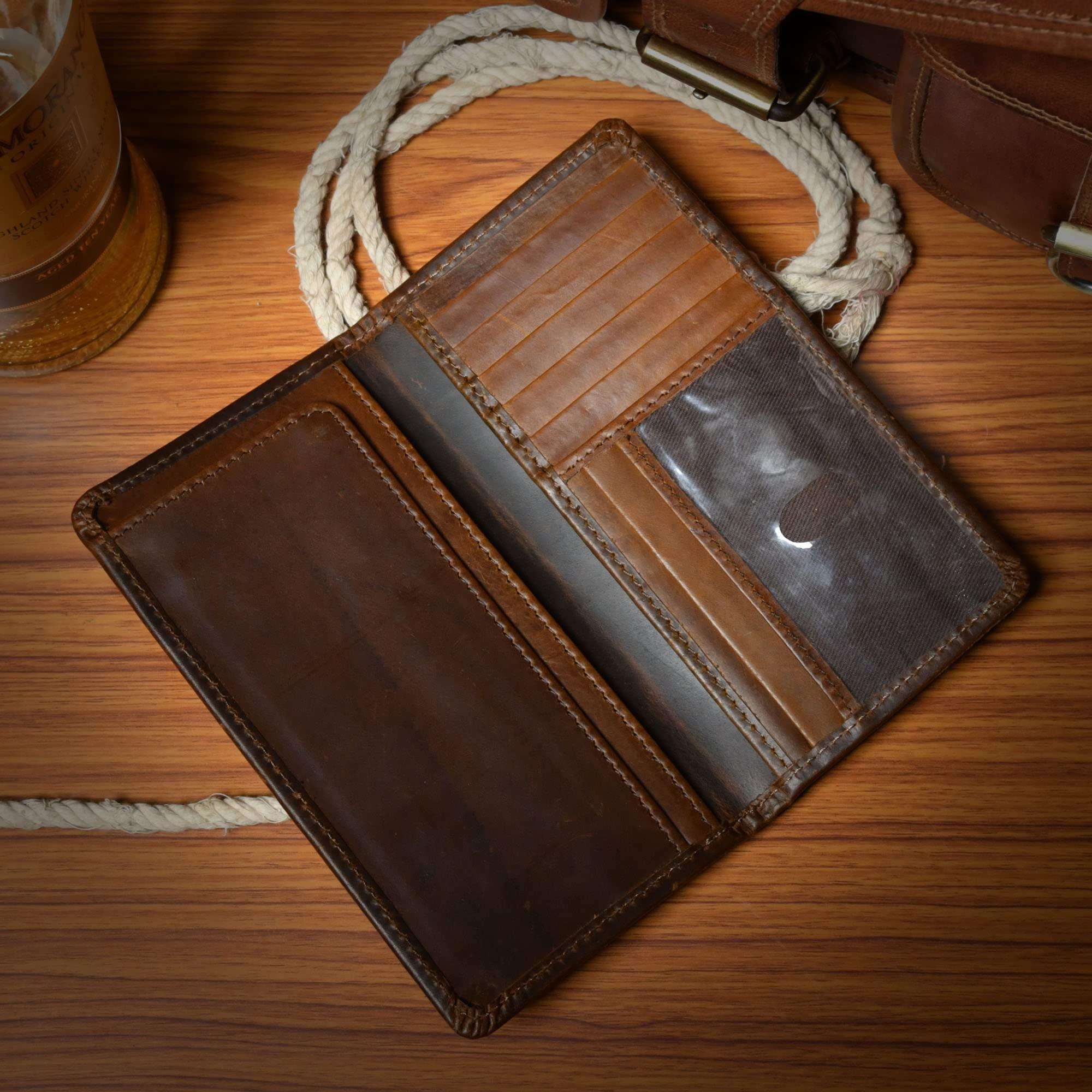 Open brown leather bifold wallet displaying multiple card slots and a clear ID window.