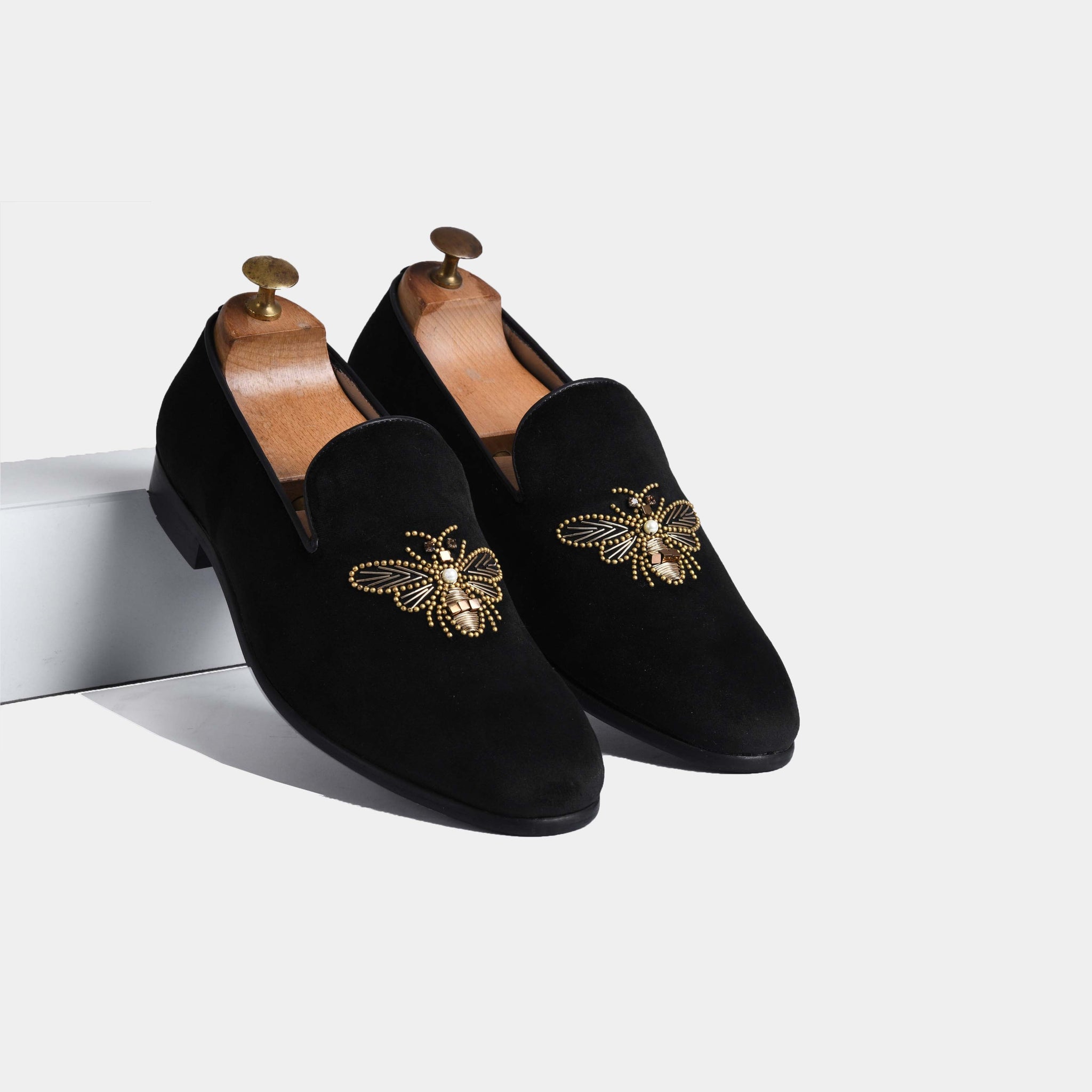 Amado Black Embroidered Leather Slip-Ons featuring a gold bee embellishment on black suede.