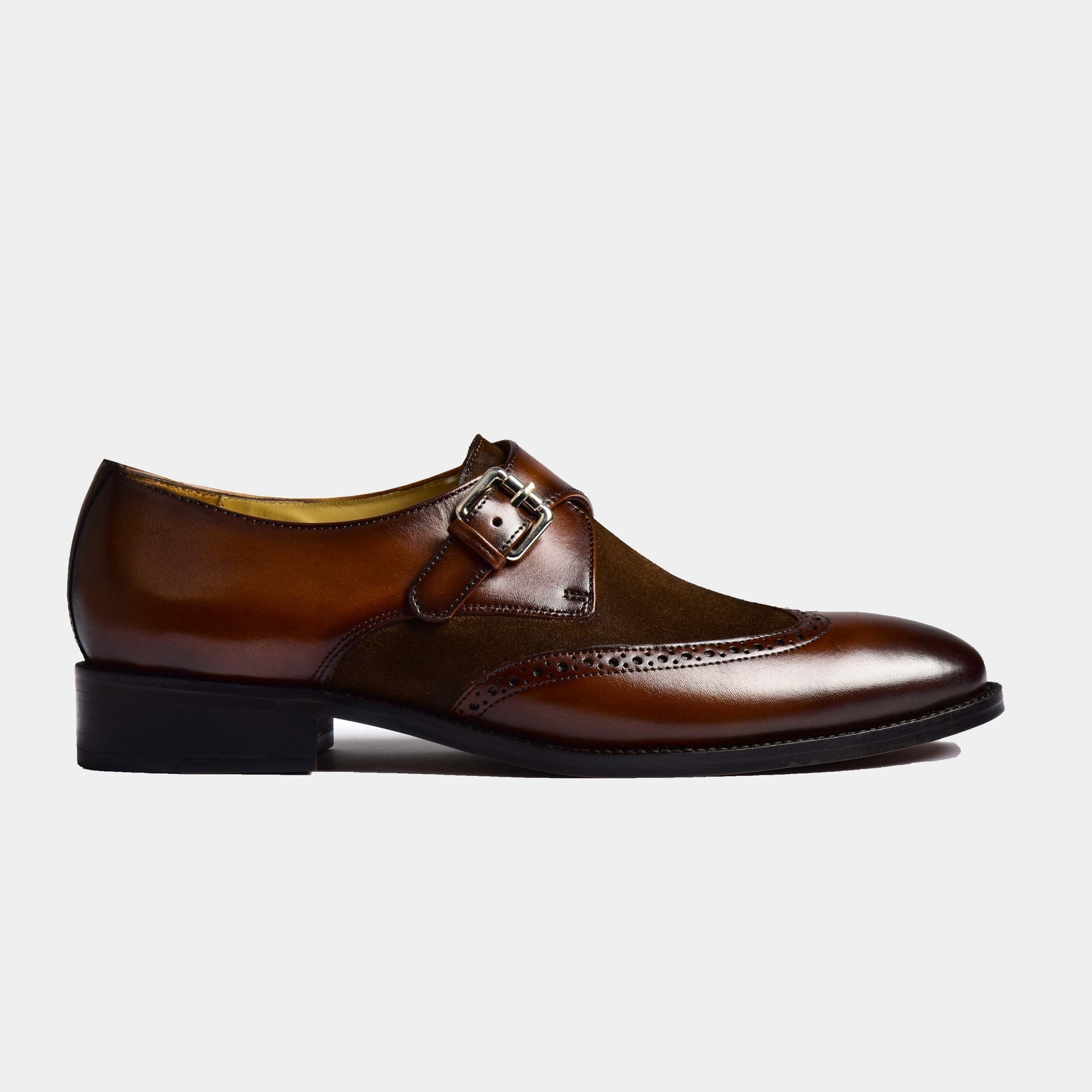 A pair of Chris Miller Leather Monk Straps in brown leather with a wingtip toe and suede accent panel, fastened with a silver buckle.