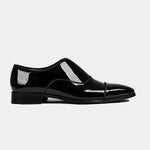 A pair of sleek black Luix Patent Leather Loafers, showcasing their polished shine and classic design in a side profile.