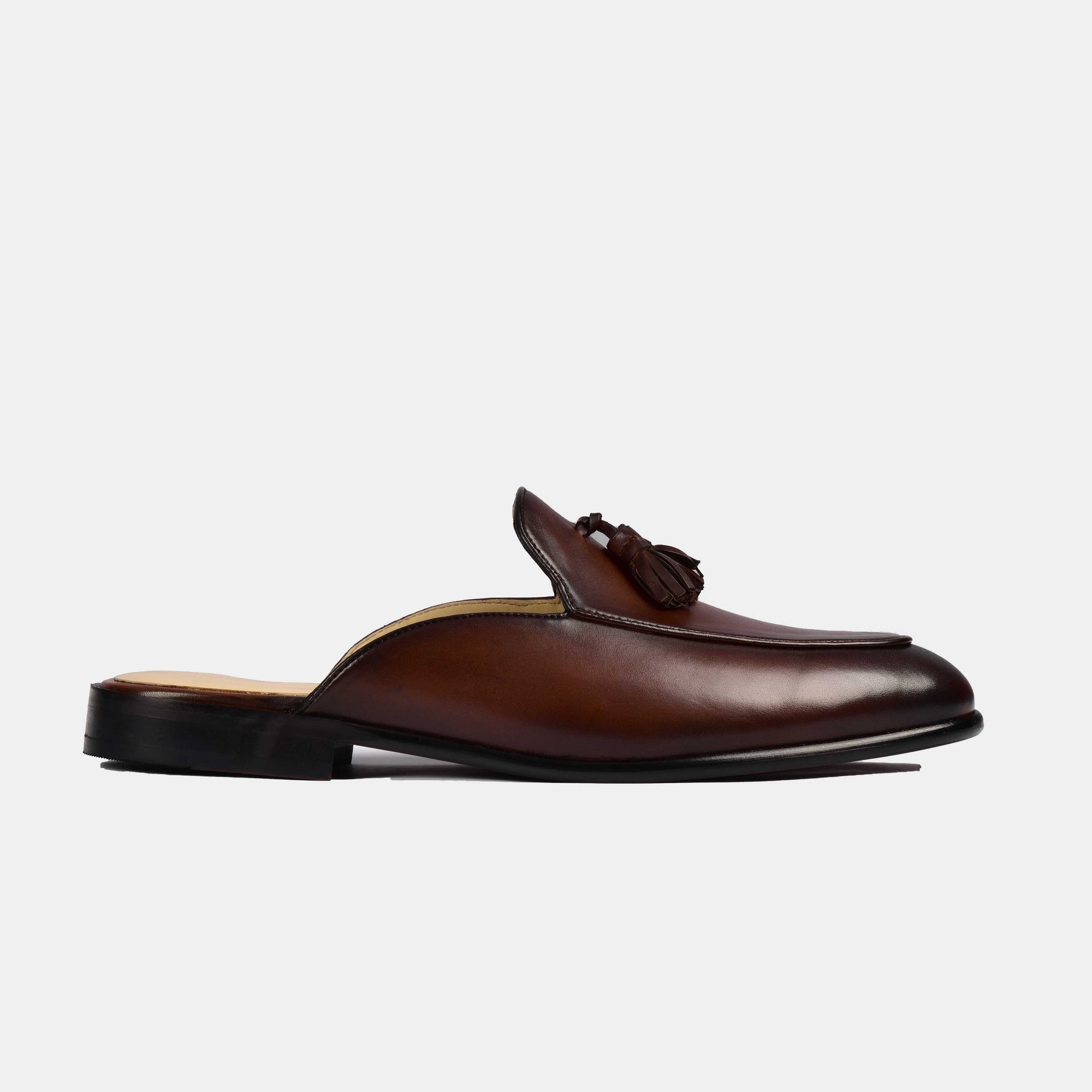 Pair of brown leather Arno mules with tassel detail, showcasing their sleek design and formal style.