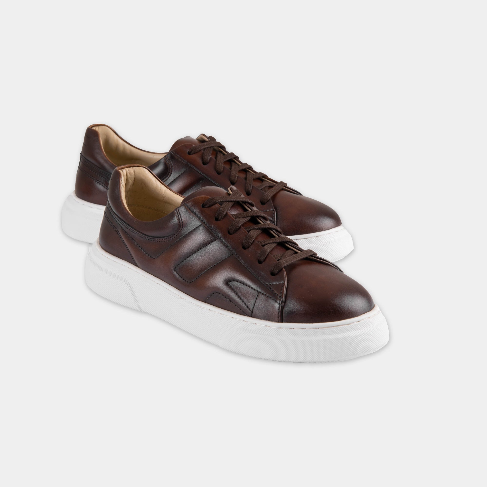 Pair of Luxoro Signature brown leather sneakers with white soles, showcasing their stylish design.