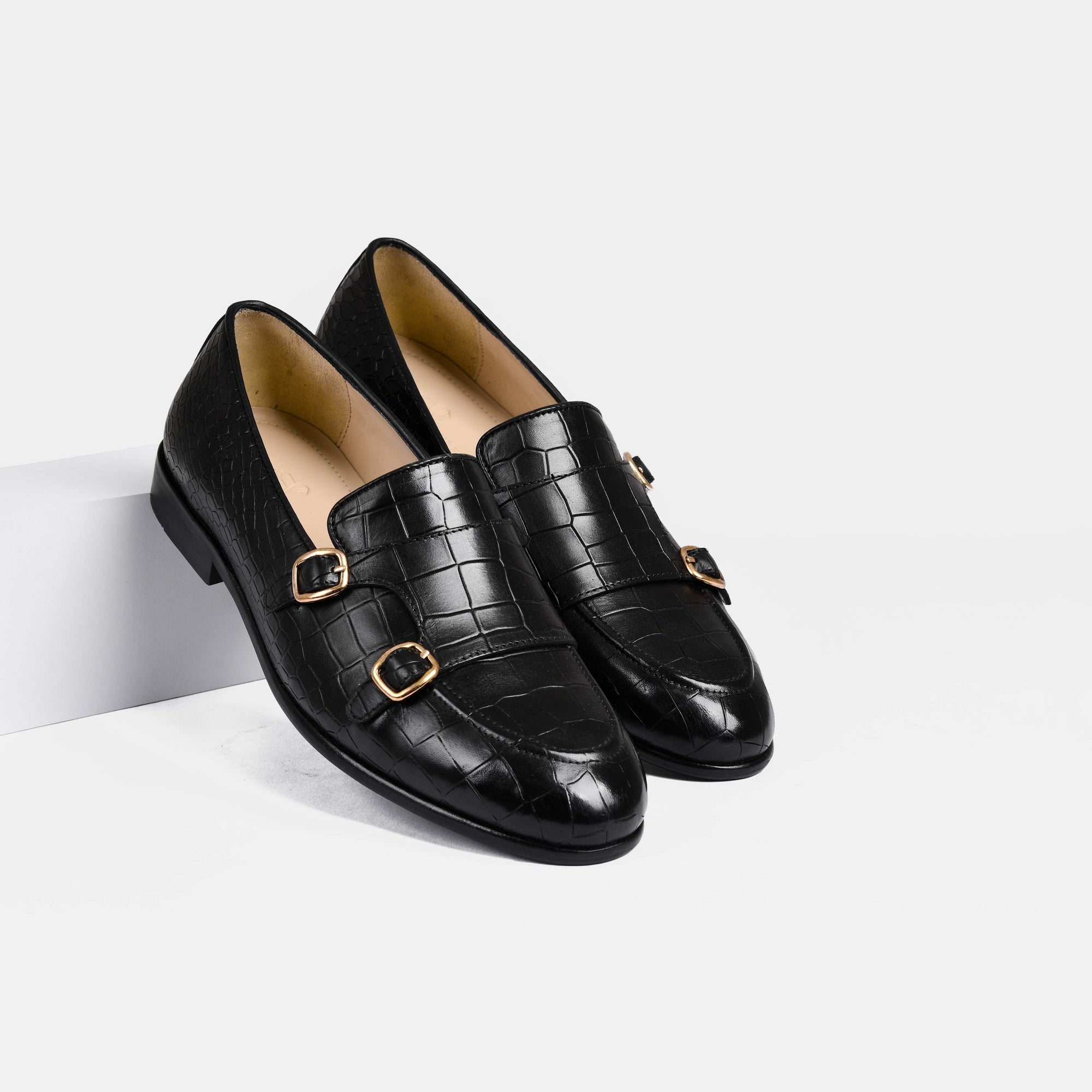 Pair of Valeria Croc Black Leather Monk Straps with gold buckles on a white background.