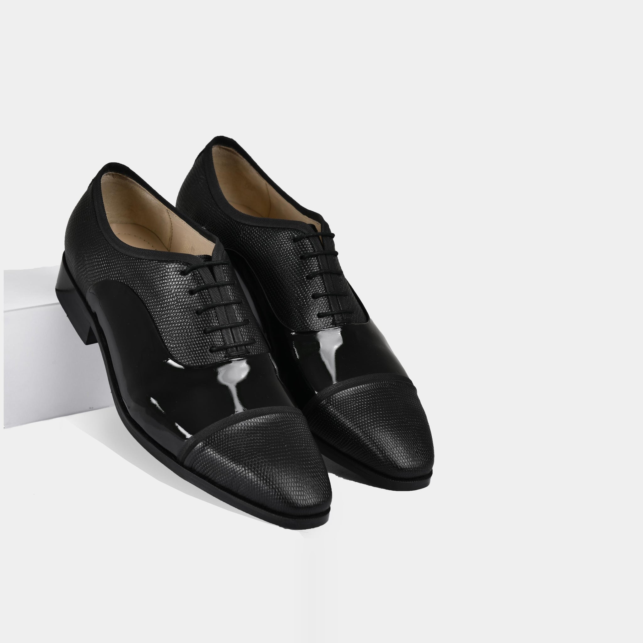 Pair of Ambros Patent black leather lace-up shoes with a textured toe cap and shiny toe box.