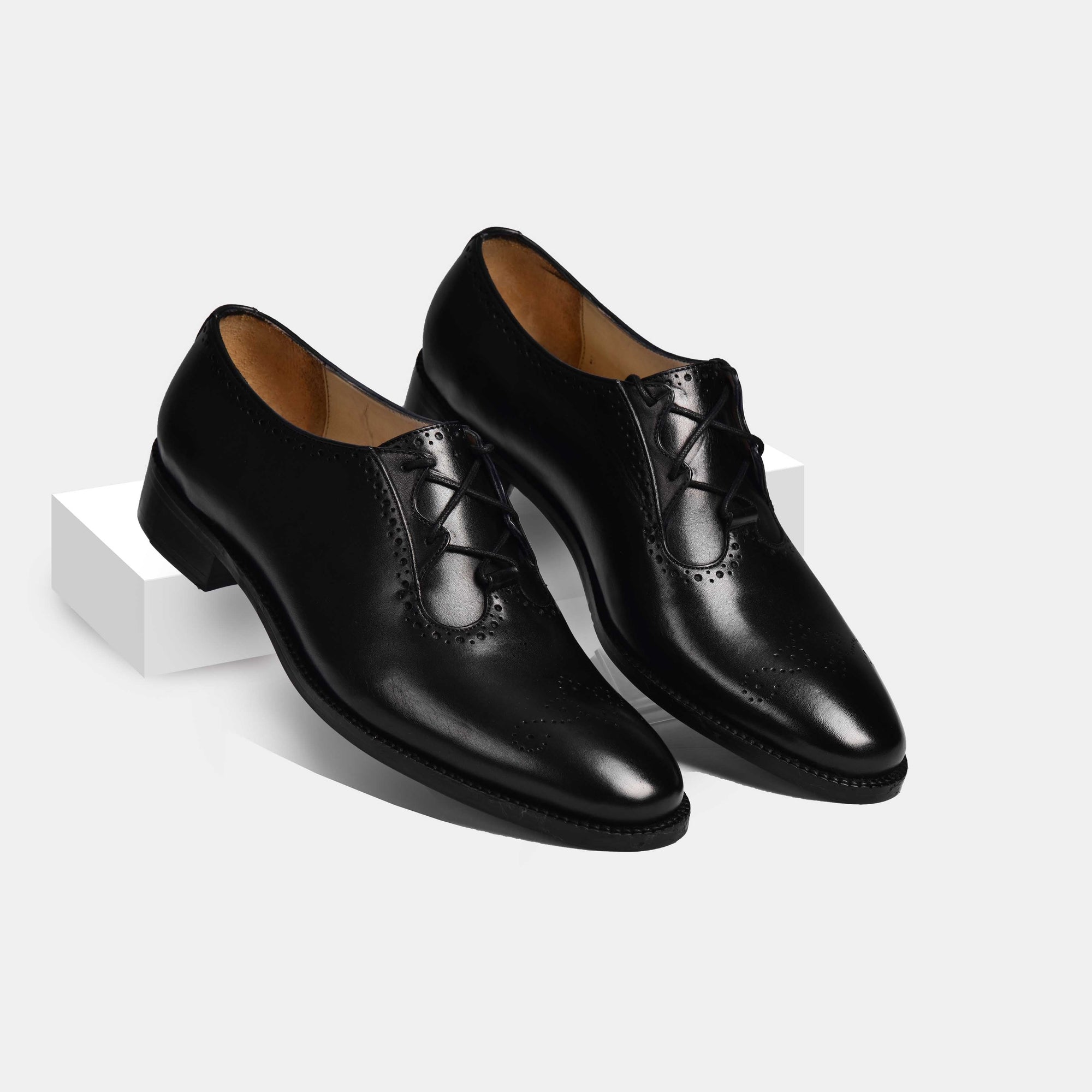 Pair of Ronald Lace Ups, black leather oxford shoes with decorative broguing, shown on a white background.