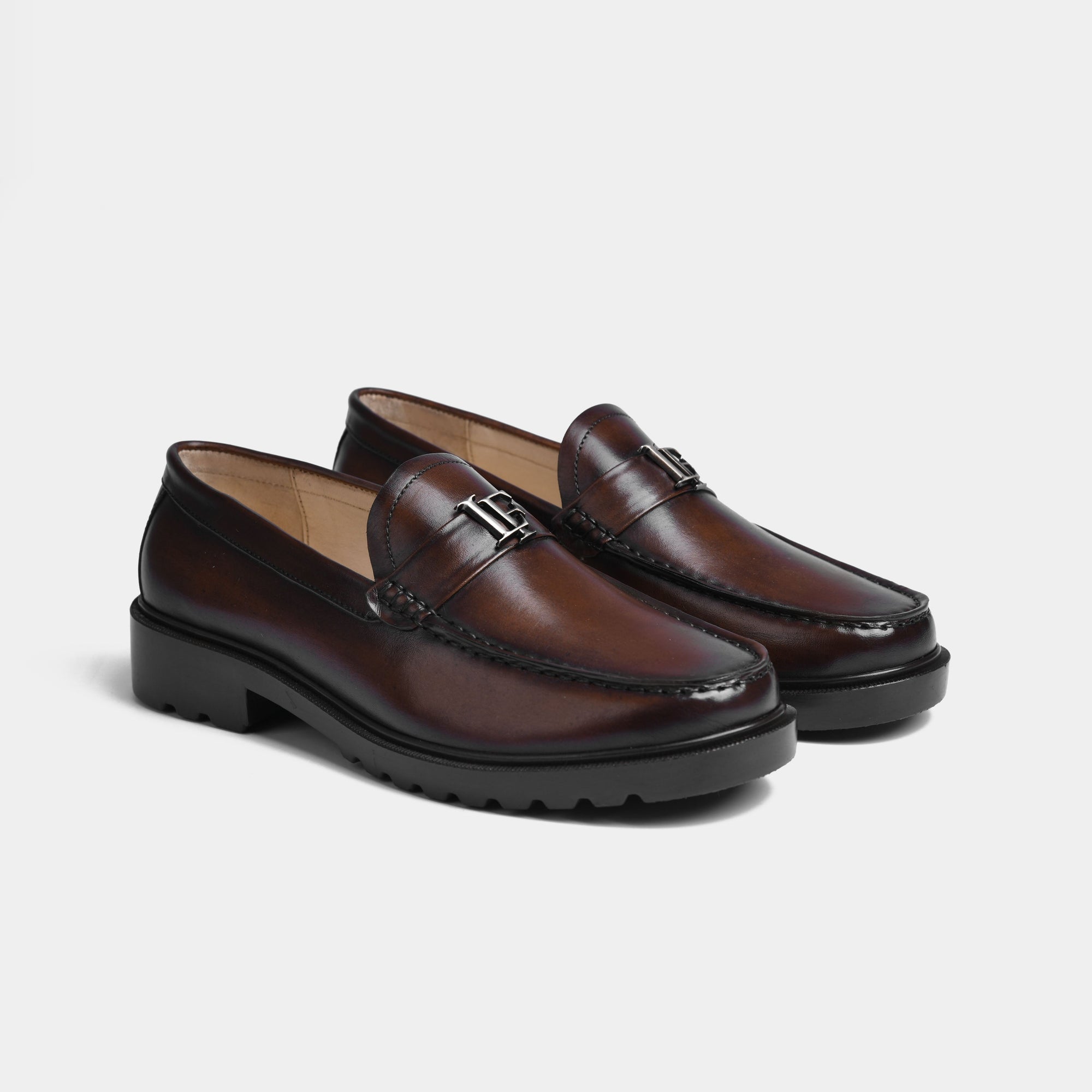 Pair of brown leather loafers with a silver metal buckle accent. Solesculpt Lite construction.