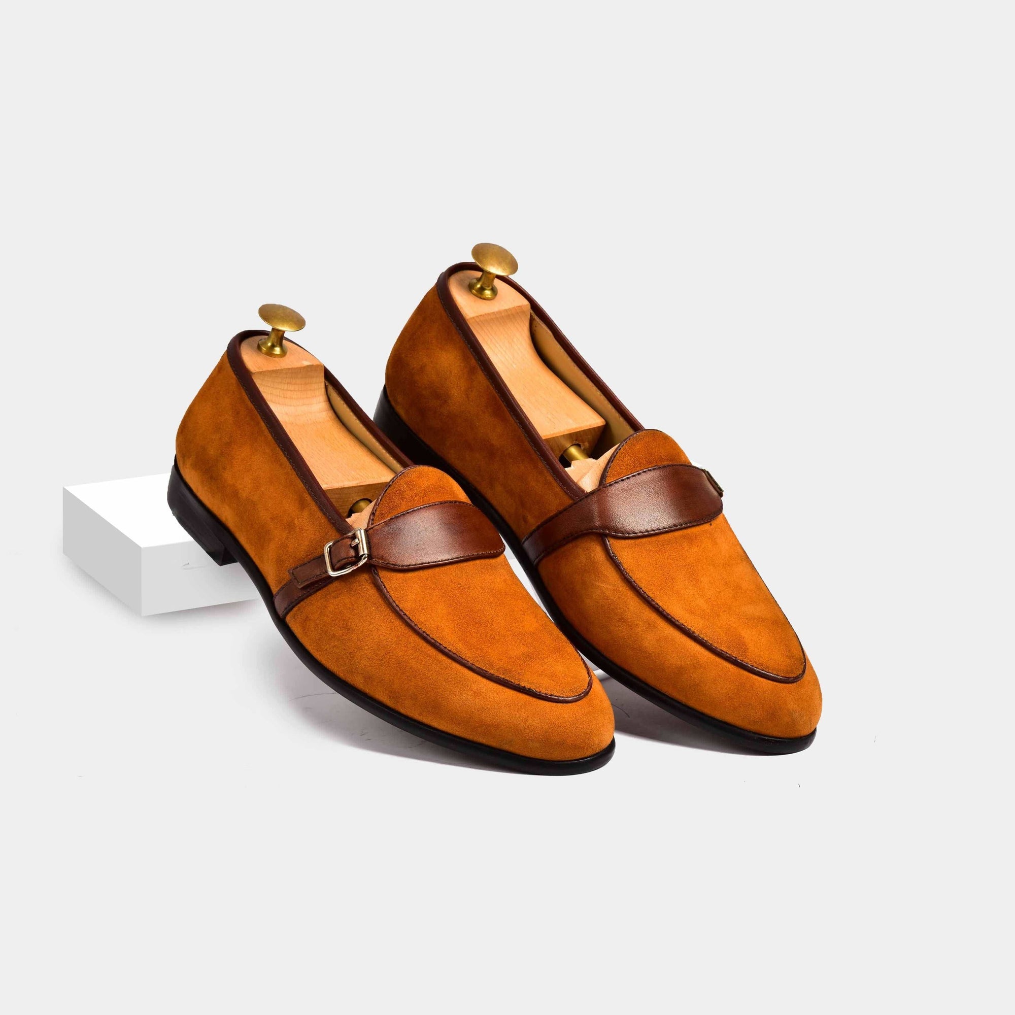 Tan suede Arno loafers with a brown leather buckle strap across the vamp.