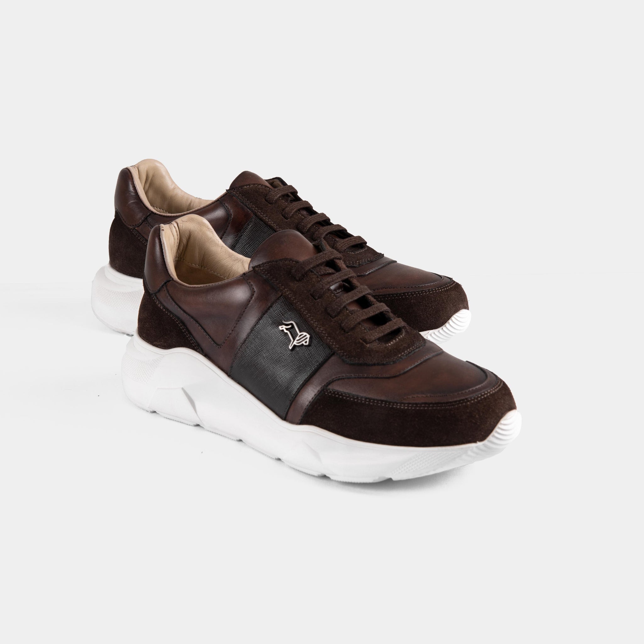 Pair of Aureo Brown leather sneakers with white soles on a white background.