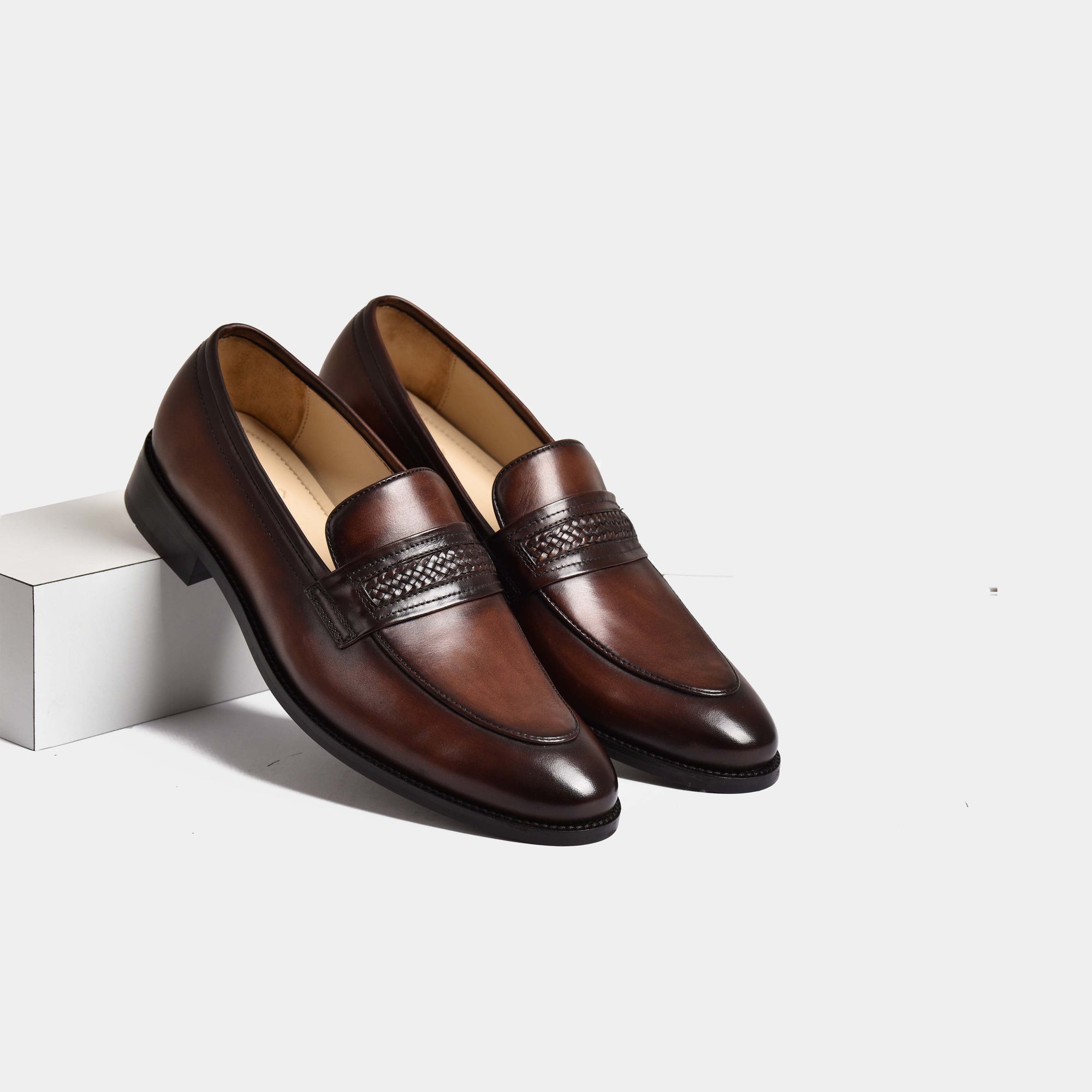 A pair of Tim Williams Leather Loafers in brown, showcasing a sleek design with a woven leather strap detail.