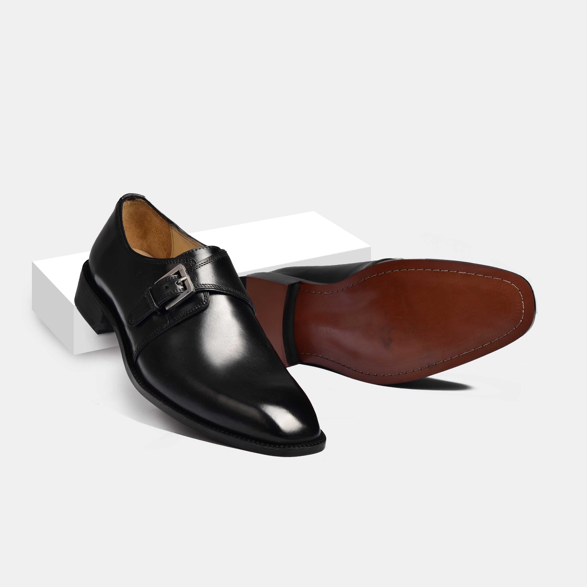 Pair of Jake Black Single Buckle Leather Monk Straps, one shoe standing upright, the other on its side showcasing the sole.